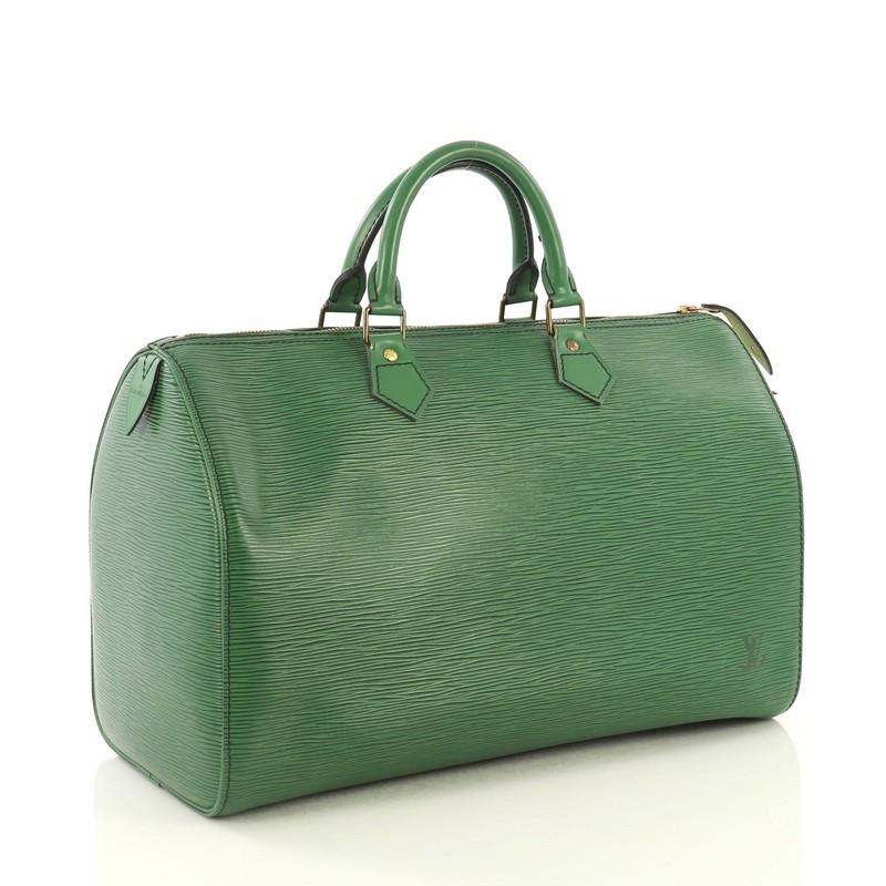 This Louis Vuitton Speedy Handbag Epi Leather 35, crafted from green epi leather, features dual rolled leather handles, exterior side pocket, and gold-tone hardware. Its zip closure opens to a green raw leather interior with slip pocket.