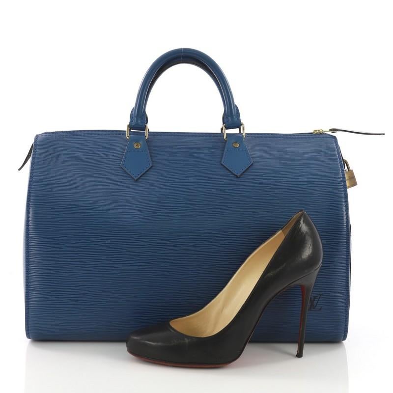 This Louis Vuitton Speedy Handbag Epi Leather 40, crafted from blue epi leather, features dual rolled leather handles, exterior side pocket and gold-tone hardware. Its zip closure opens to a green raw leather interior with slip pocket. Authenticity