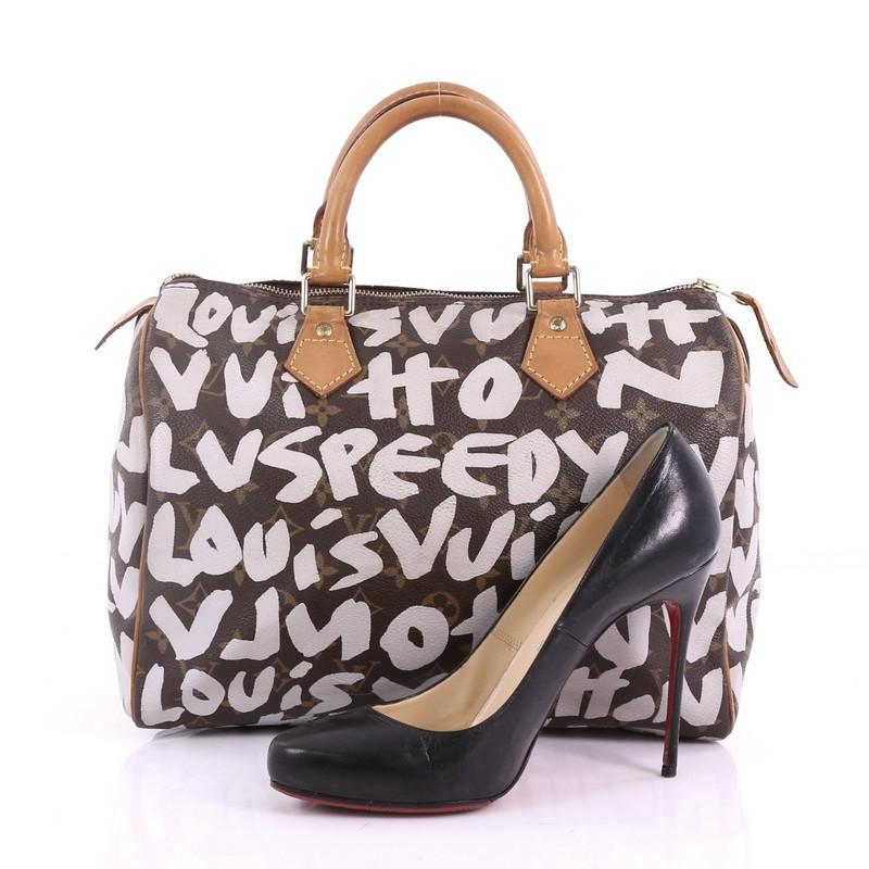 This Louis Vuitton Speedy Handbag Limited Edition Monogram Graffiti Canvas 30, crafted from brown monogram coated canvas with wnite graffiti print, features cowhide leather handles and trims and gold-tone hardware. Its zip closure opens to a brown