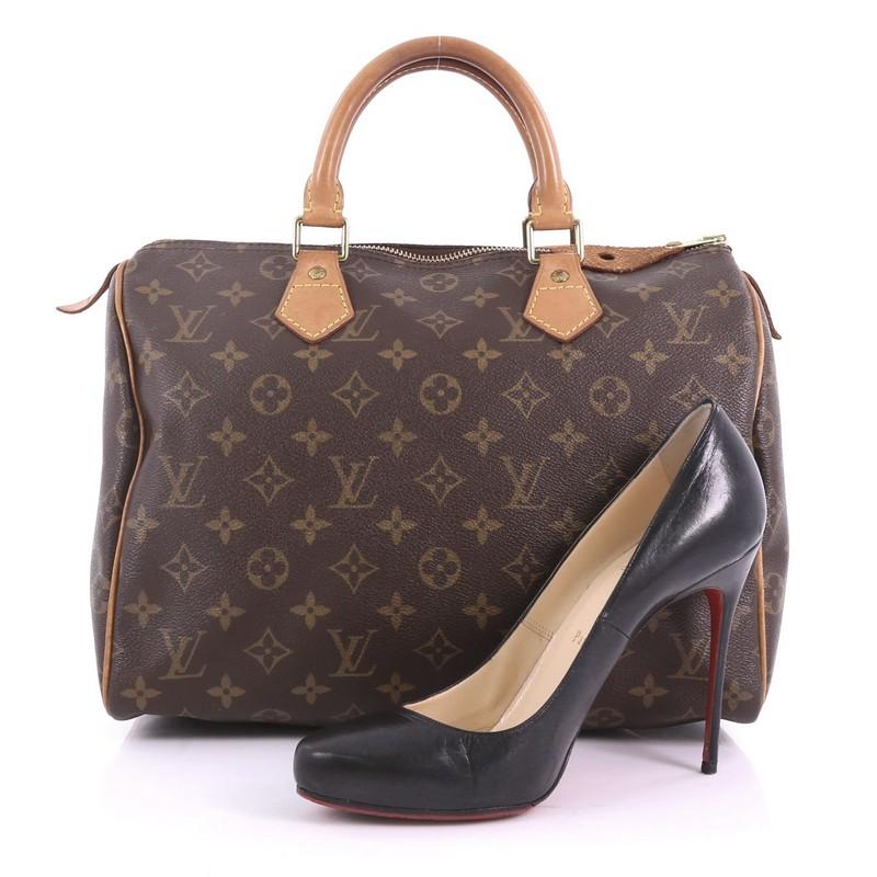 This Louis Vuitton Speedy Handbag Monogram Canvas 30, crafted in brown monogram coated canvas, features dual-rolled leather handles, vachetta leather trims, and gold-tone hardware. Its zip closure opens to a brown fabric interior with slip pocket.