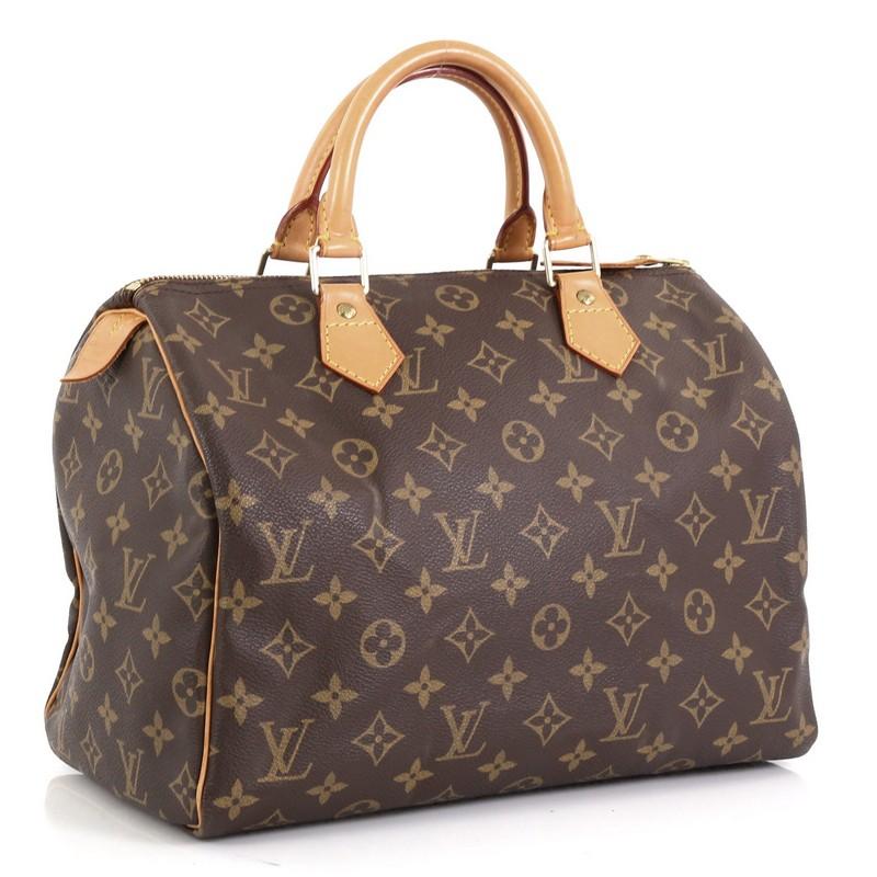 This Louis Vuitton Speedy Handbag Monogram Canvas 30, crafted in brown monogram coated canvas, features dual rolled leather handles, vachetta leather trim, and gold-tone hardware. Its zip closure opens to a brown fabric interior with slip pocket.