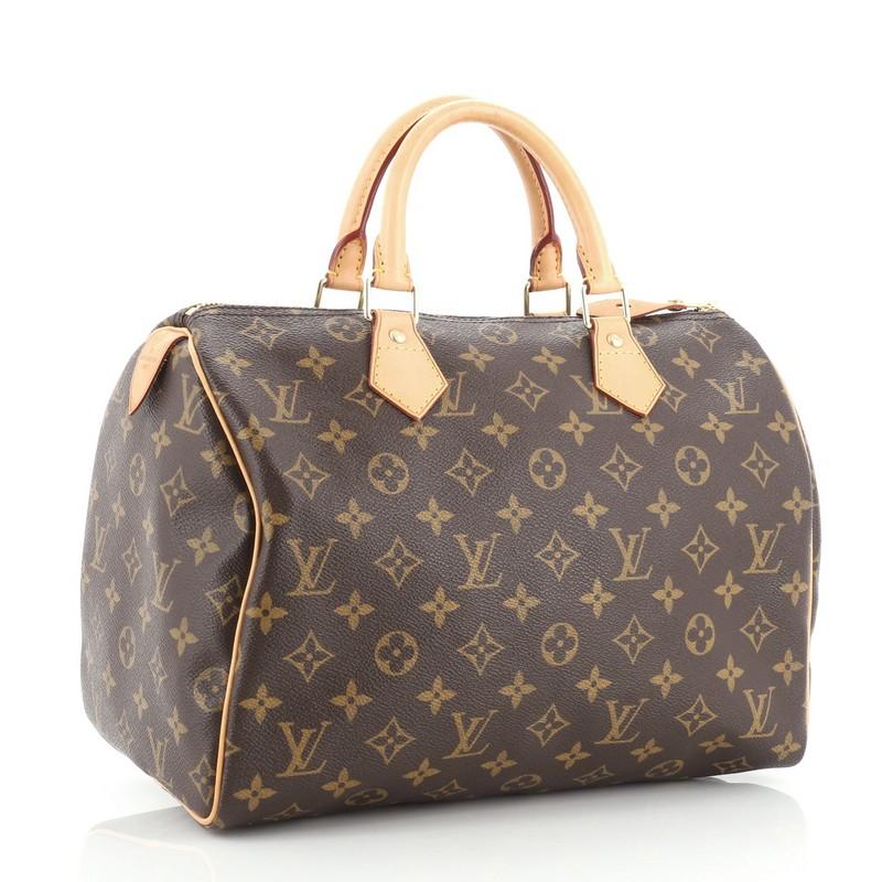 This Louis Vuitton Speedy Handbag Monogram Canvas 30, crafted in brown monogram coated canvas, features dual rolled leather handles, vachetta leather trim, and gold-tone hardware. Its zip closure opens to a brown fabric interior with slip pocket.