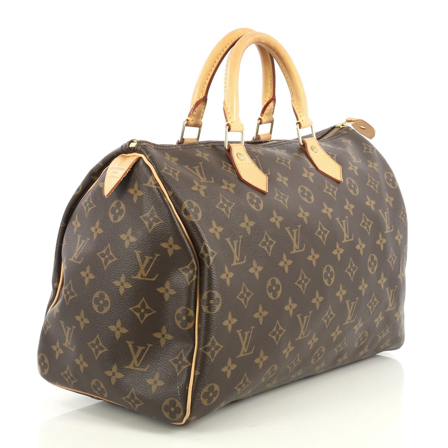 This Louis Vuitton Speedy Handbag Monogram Canvas 35, crafted in brown monogram coated canvas, features dual rolled leather handles, vachetta leather trim, and gold-tone hardware. Its zip closure opens to a brown fabric interior with slip pocket.