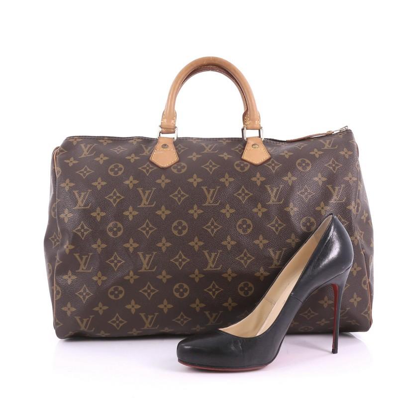 This Louis Vuitton Speedy Handbag Monogram Canvas 40, crafted in brown monogram coated canvas, features dual rolled leather handles, vachetta leather trims, and gold-tone hardware. Its top zip closure opens to a brown fabric interior with slip
