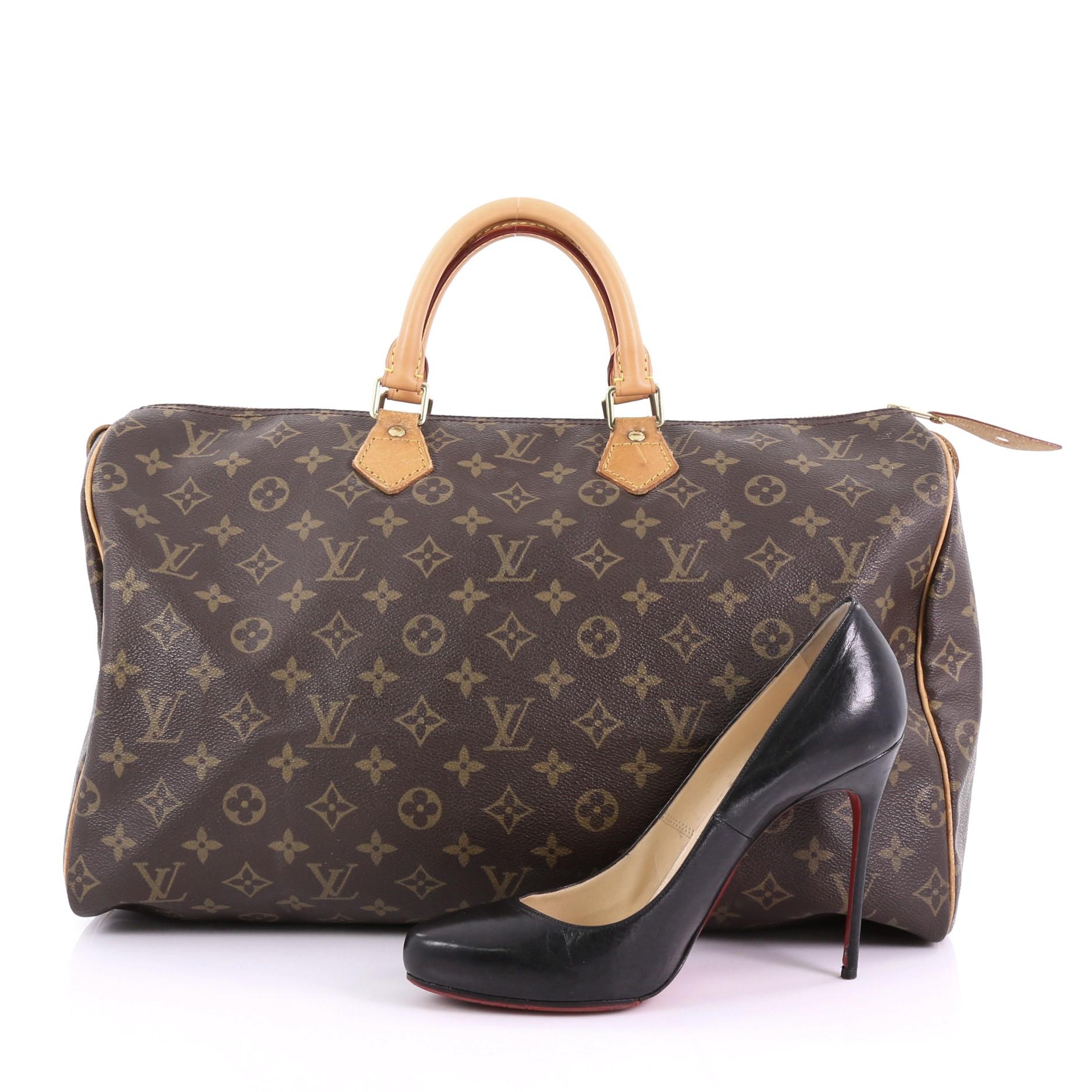 This Louis Vuitton Speedy Handbag Monogram Canvas 40, crafted in brown monogram coated canvas, features dual rolled leather handles, vachetta leather trims, and gold-tone hardware. Its top zip closure opens to a brown fabric interior with slip