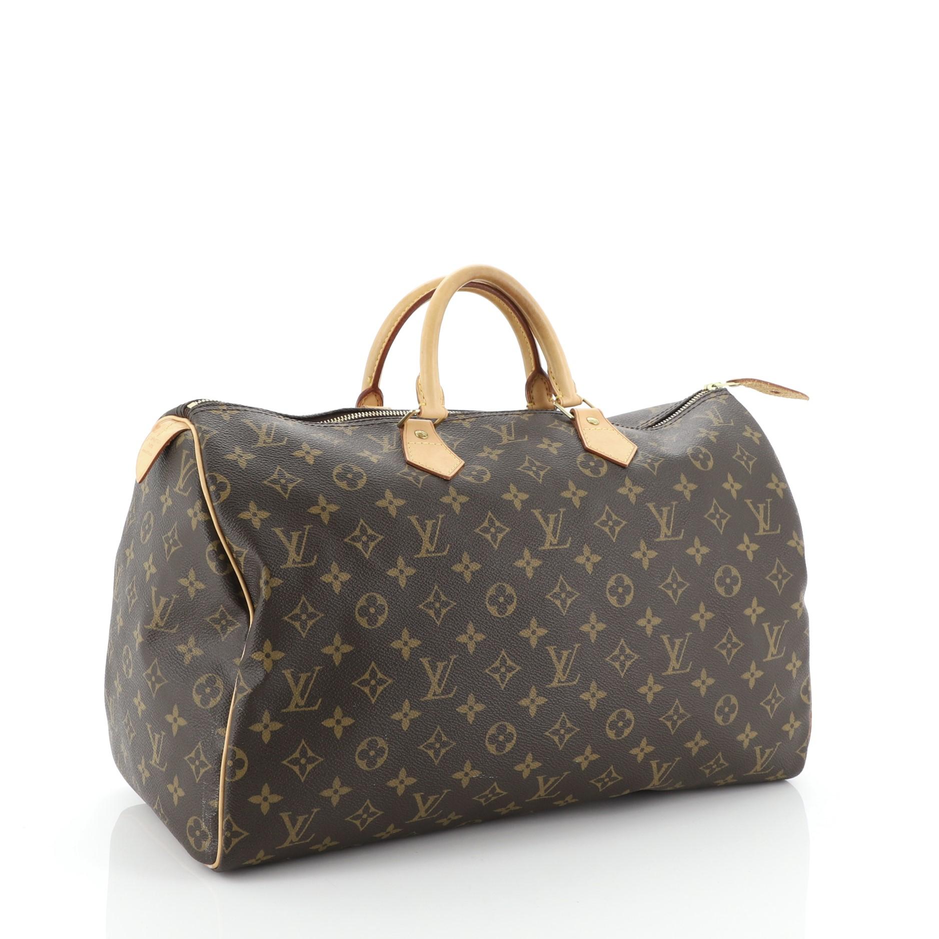 This Louis Vuitton Speedy Handbag Monogram Canvas 40, crafted in brown monogram coated canvas, features dual rolled leather handles, vachetta leather trim, and gold-tone hardware. Its zip closure opens to a brown fabric interior with zip pocket.