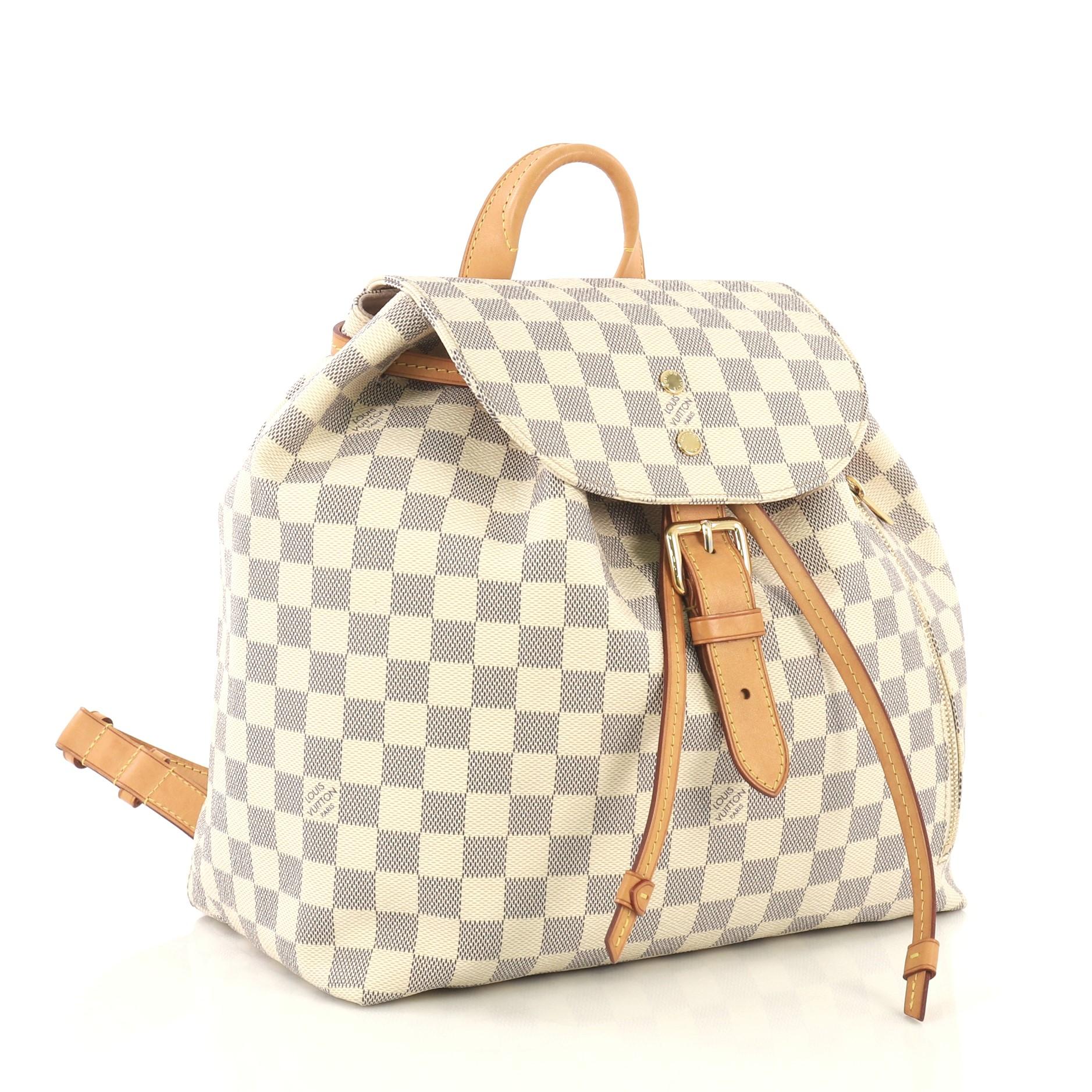 This Louis Vuitton Sperone Backpack Damier, crafted from damier azur coated canvas, features top leather handle, adjustable flat shoulder straps, exterior zip pocket, and gold-tone hardware. Its buckle and drawstring closure opens to a pink