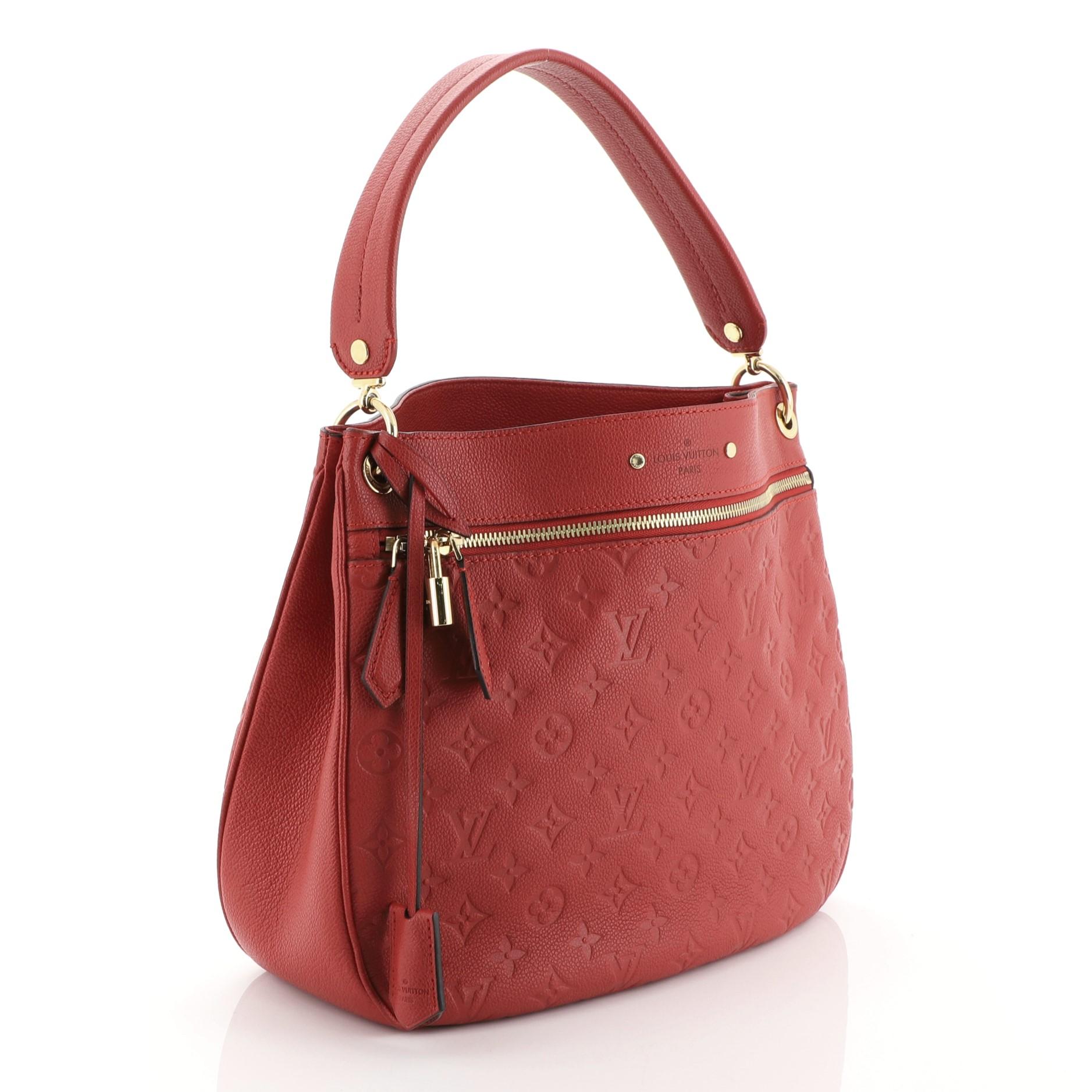 This Louis Vuitton Spontini NM Handbag Monogram Empreinte Leather, crafted from red monogram empreinte leather, features a flat leather strap, exterior front zip pocket, protective base studs, and gold-tone hardware. It opens to a red fabric