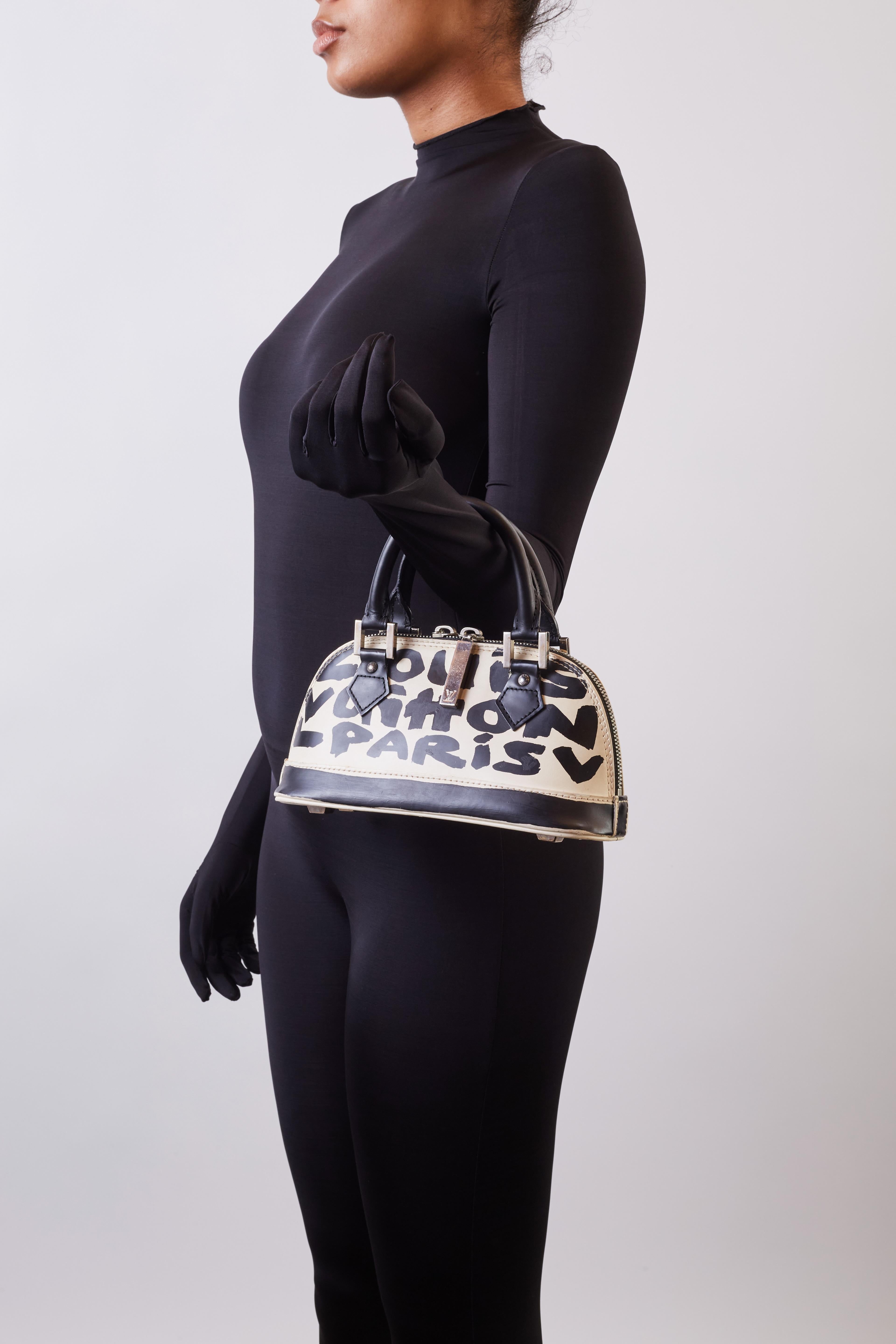 This Alma MM handbag by Stephen Sprouse comes with in white with a layer of Sprouse inspired Graffiti reading Louis Vuitton Paris.
This bag is crafted of white leather printed with lv brand in black on white. The bag features dual rolled leather top