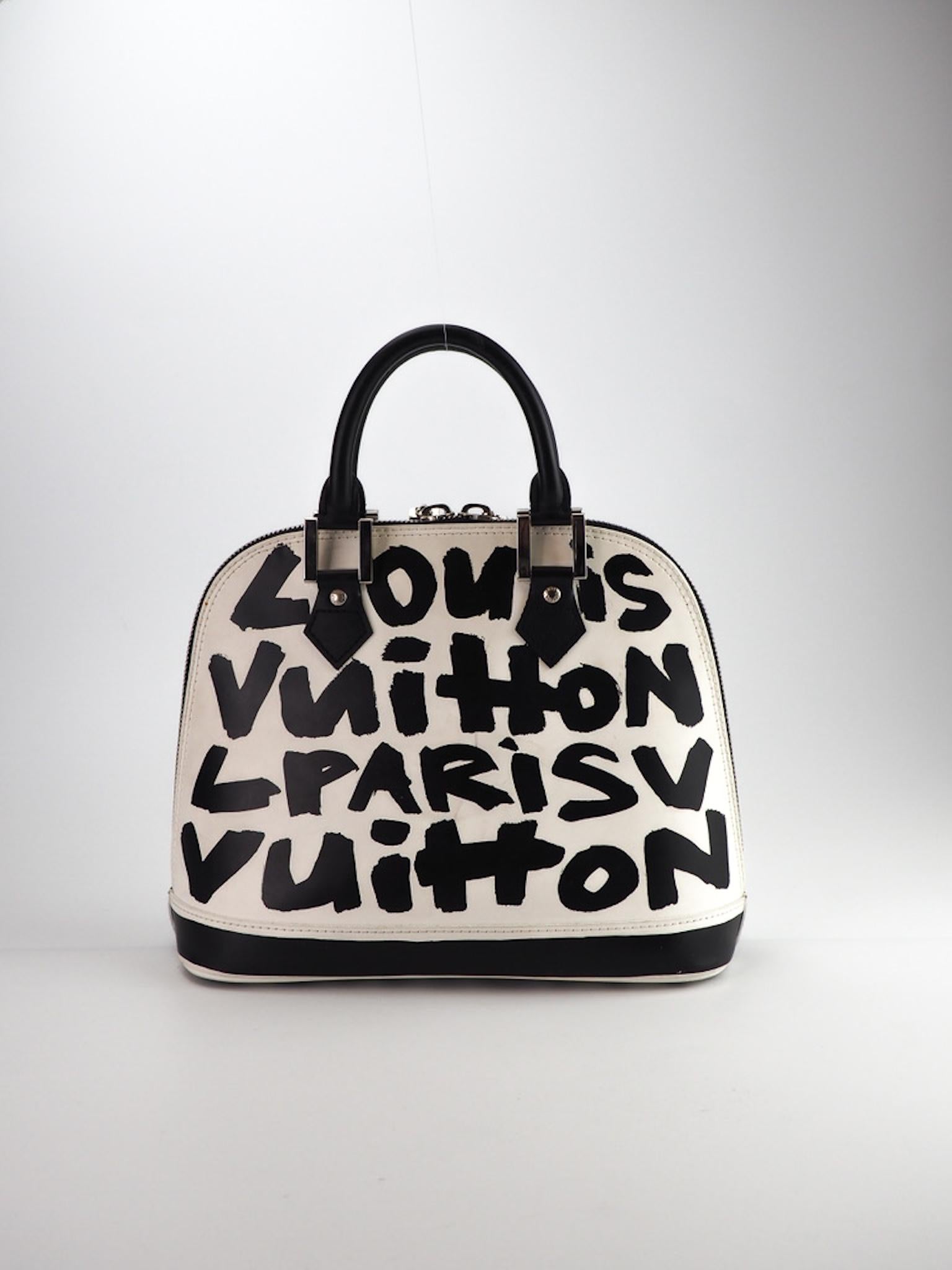 This Stephen Sprouse Alma handbag is made of coated canvas with a layer of white printing with an additional Sprouss inspired black Graffiti layer reading Louis Vuitton Paris. The bag features dual rolled leather top handles, geometric silver links,