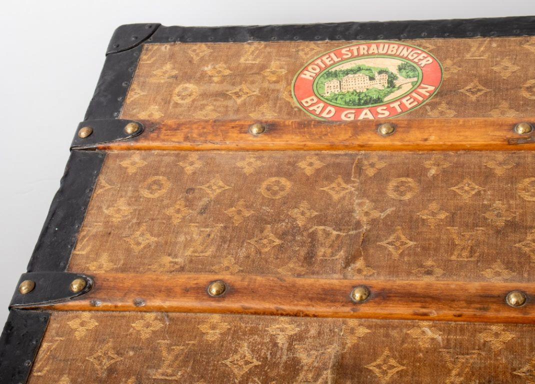 Louis Vuitton Steamer Trunk, Early 20th Century, in LV monogrammed pattern with metal side handles and fittings, decoupaged stickers to all fours sides and top, lock inscribed 