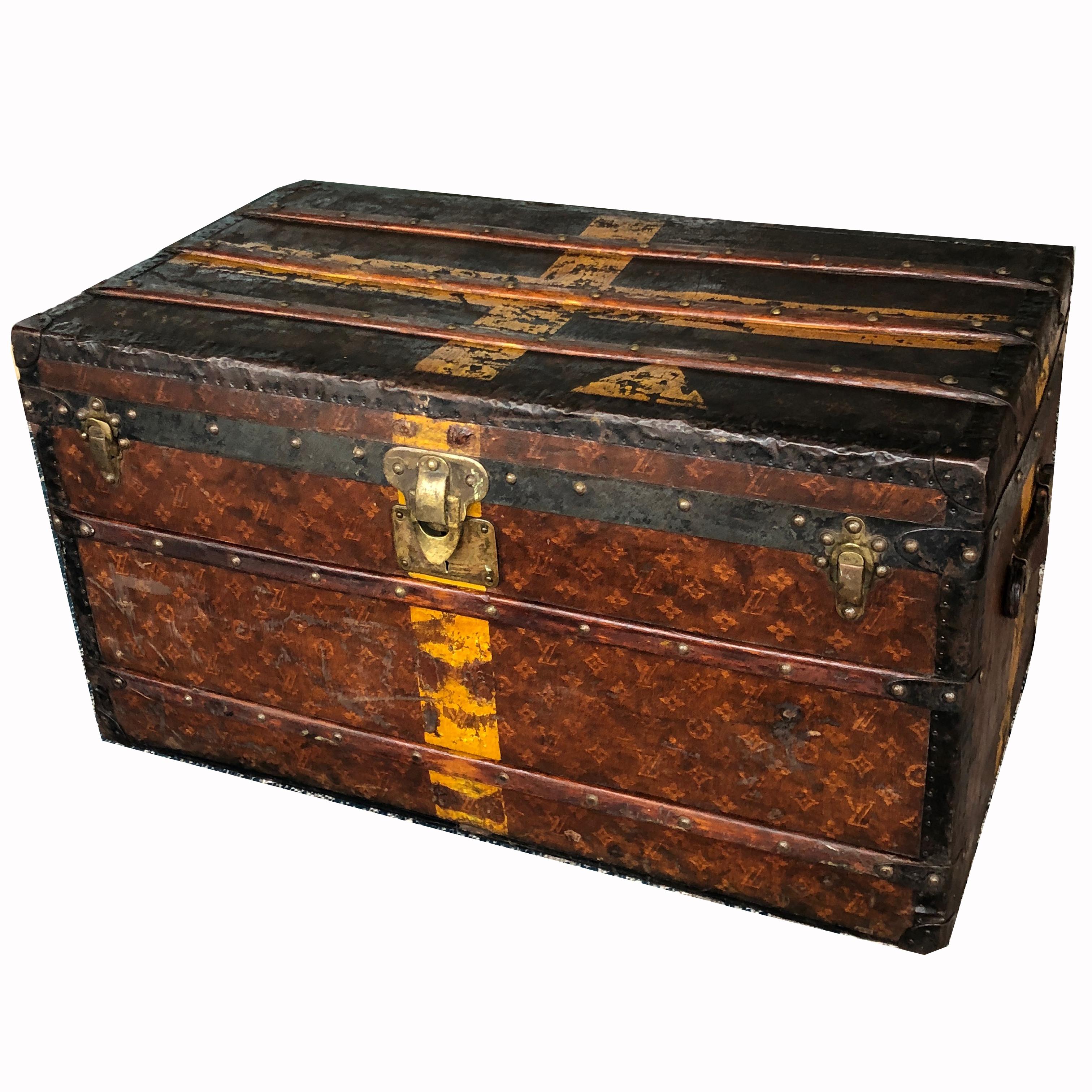 Authentic, antique Louis Vuitton monogram canvas steamer trunk from the early 20th C. Woven canvas, metal trim, leather handles with four wheels at the bottom. A key is included which still works to lock the primary latch. Three canvas & wood