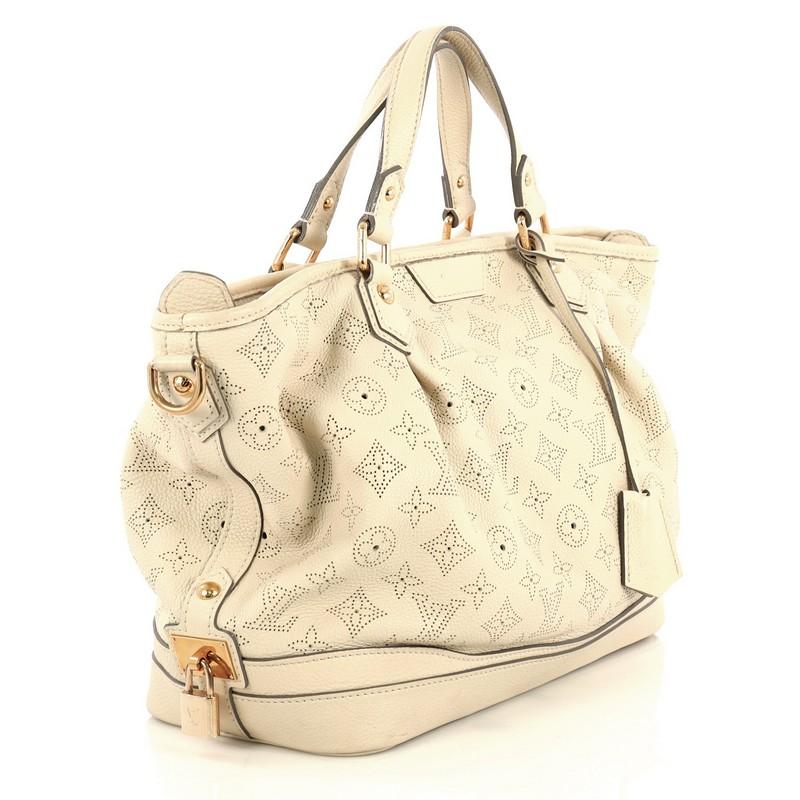 This Louis Vuitton Stellar Handbag Mahina Leather PM, crafted from neutral perforated mahina leather, features dual flat leather handles, inverted pleat details, leather trim, protective base studs, and gold-tone hardware. Its zip closure opens to a