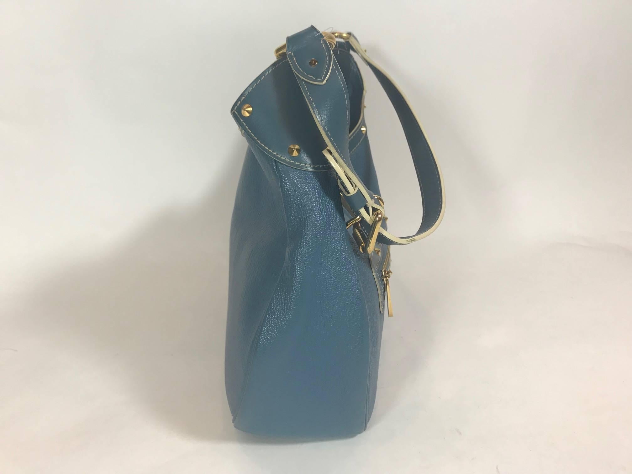 From the well-loved Suhali Leather Collection comes this rare and discontinued Louis Vuitton bag. Crafted in France of luxurious blue deeply grained goat leather, this over the shoulder bag is adorned with a LV engraved polished golden metal S-lock