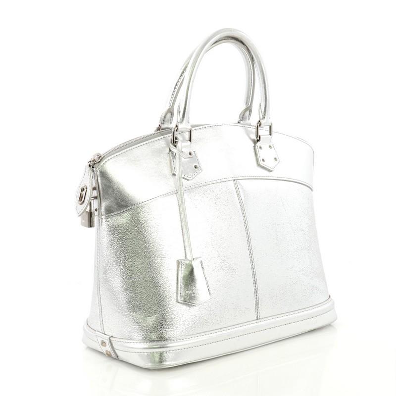 This Louis Vuitton Suhali Lockit Handbag Leather MM, crafted from metallic silver leather, features dual rolled handles and silver-tone hardware. Its zip closure opens to a gray fabric interior with side zip and slip pockets. Authenticity code