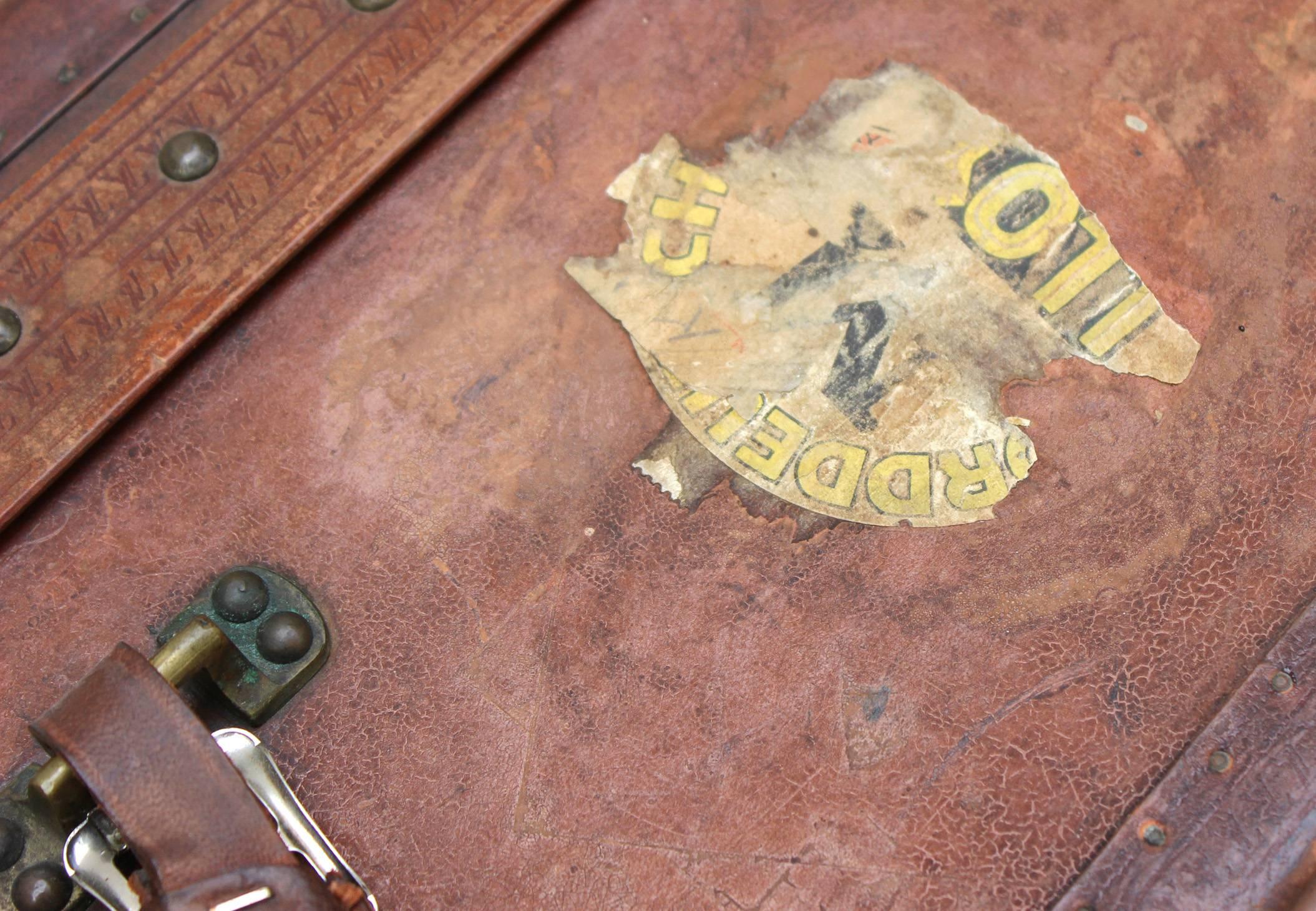 Vintage Louis Vuitton suitcase finished in brown leather, inclusive of pieces of original hotel stickers from a bygone era.
 