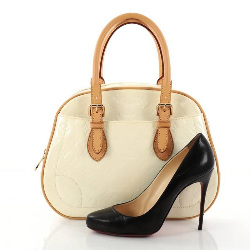 This authentic Louis Vuitton Summit Drive Handbag Monogram Vernis is perfect for on the go moments. Crafted in beige monogram vernis leather, this structured satchel features dual-rolled vachetta leather belted handles and trims, exterior pockets