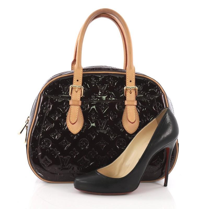 This Louis Vuitton Summit Drive Handbag Monogram Vernis, crafted from dark purple monogram vernis leather, features dual rolled belted handles, exterior pockets and gold-tone hardware. Its top zip closure opens to a brown fabric interior with slip