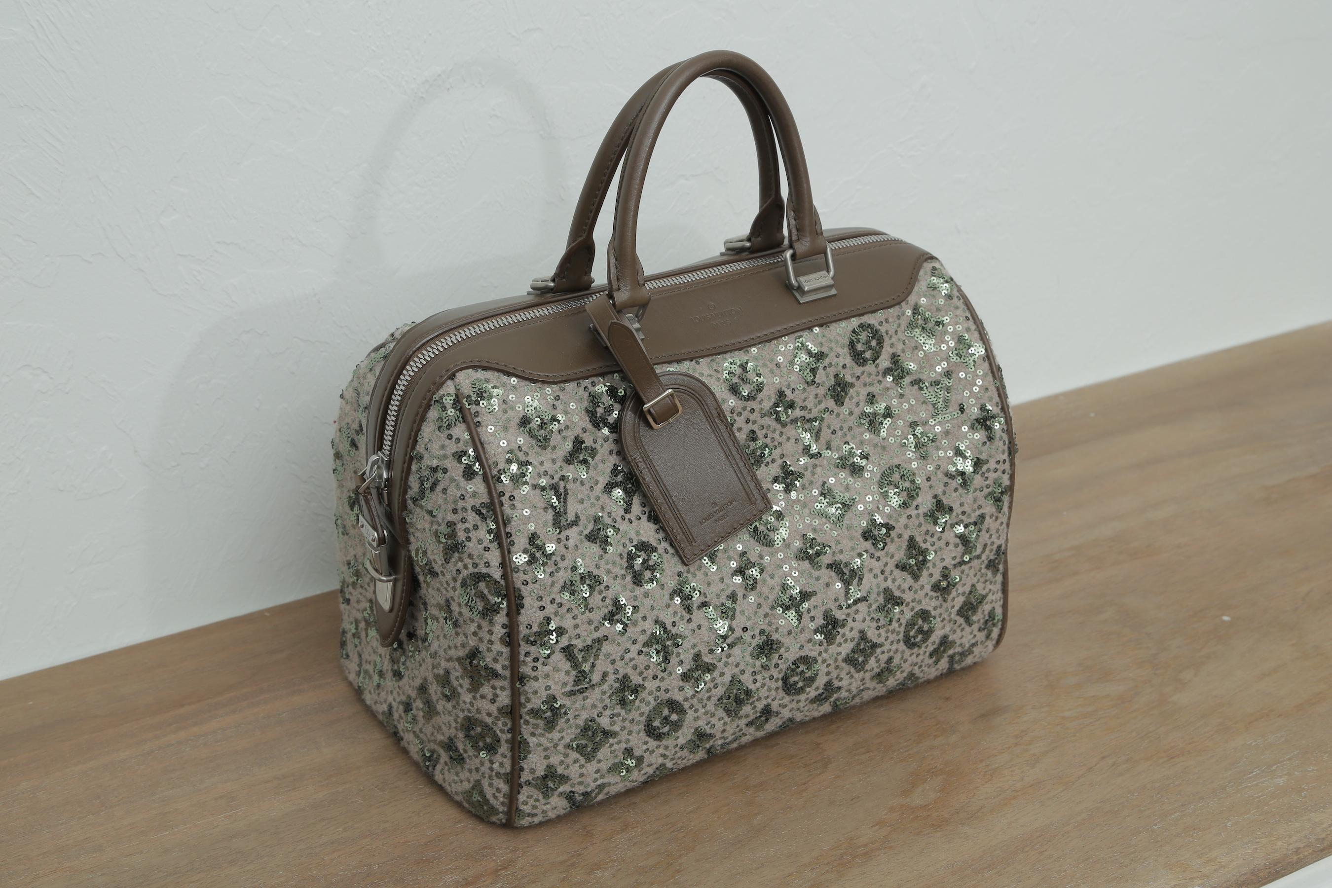 This Louis Vuitton Speedy is entirely covered in an embellishment of green sequin Louis Vuitton monogram on a beige tweed fabric background. This limited edition bag features two brown rolled leather top handles and leather trim with matte silver