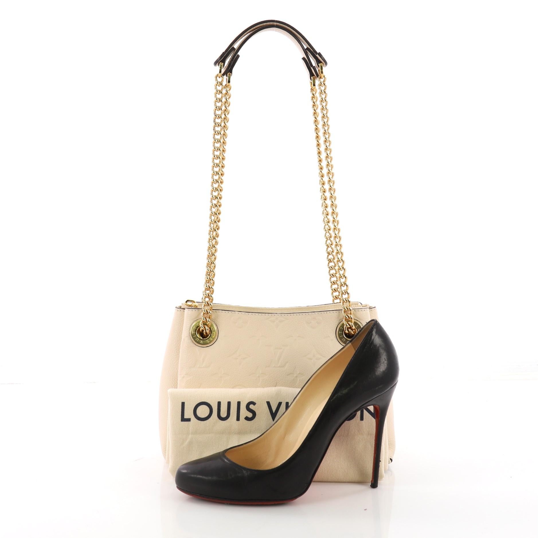 This Louis Vuitton Surene Handbag Monogram Empreinte Leather BB, crafted from cream monogram empreinte leather, features dual chain link straps with leather pads and gold-tone hardware, It opens to a cream microfiber interior showcasing three