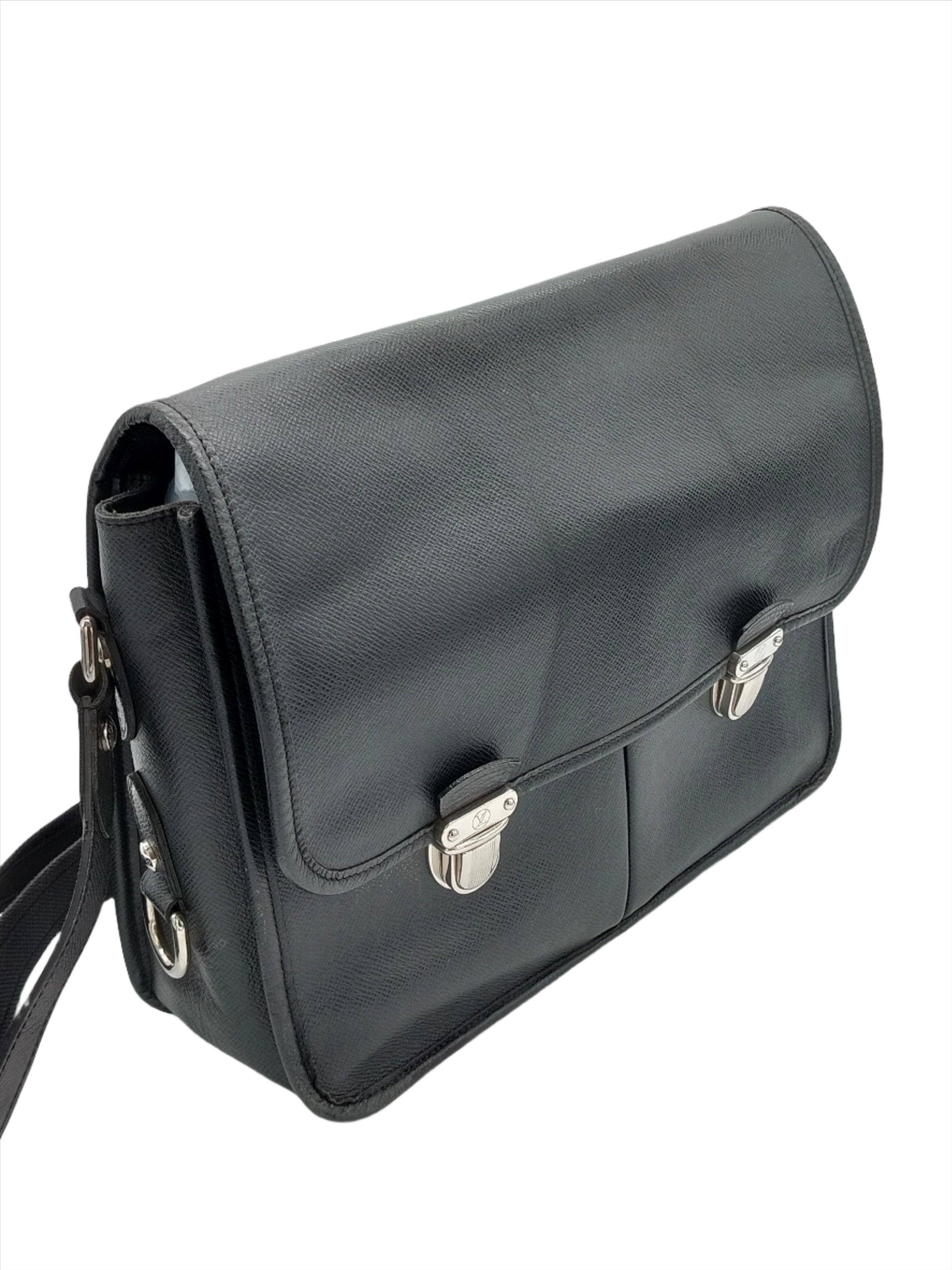 Crafted from black taiga leather, the Louis Vuitton Alexei messenger bag features a long adjustable fabric strap, a front flap, two front pockets under the flap, a back exterior slip pocket and silver-tone hardware. The push-lock closure opens to a