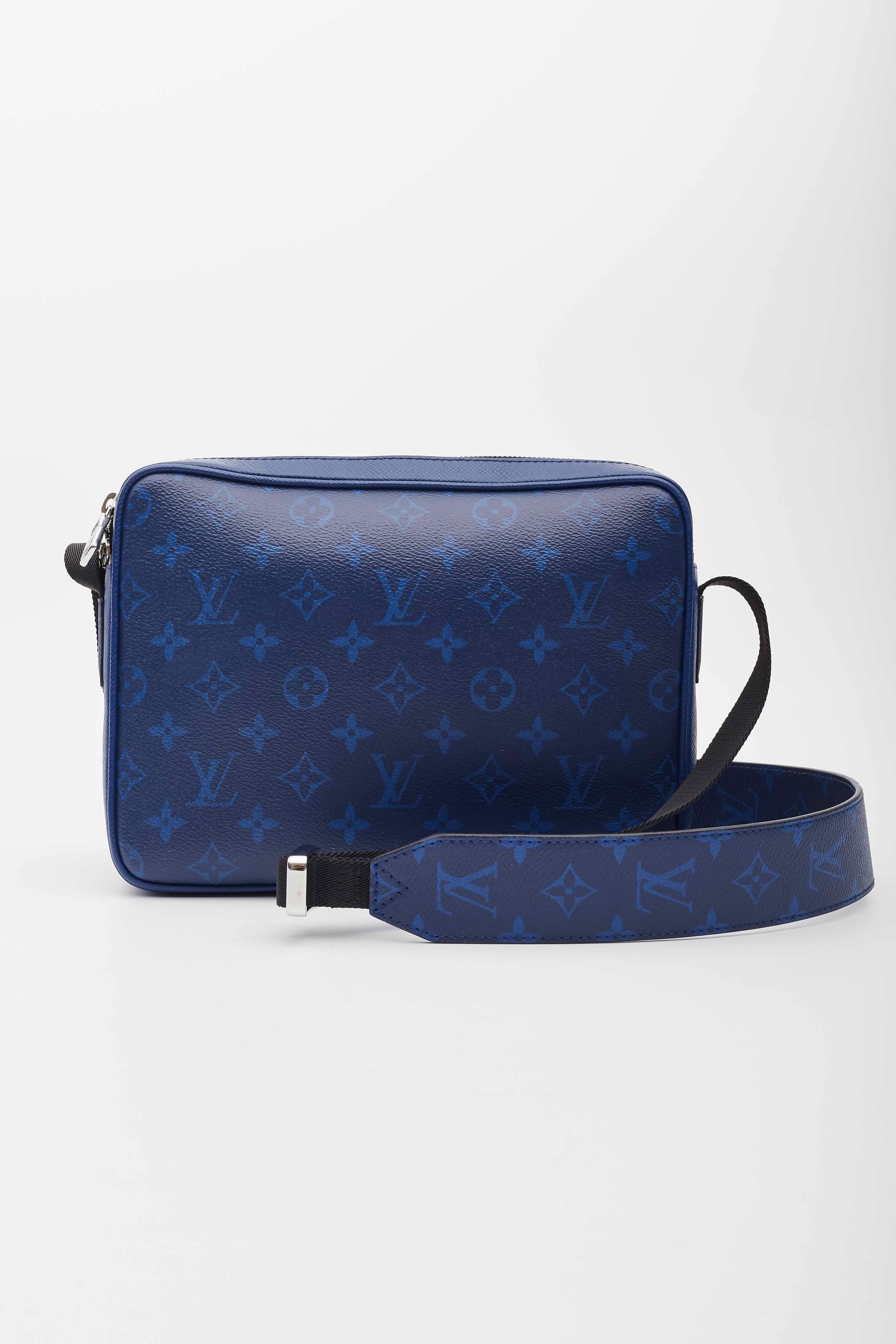 This messenger bag is made of royal blue cross-grain taiga leather, with classic Louis Vuitton monogram-coated canvas accents. The bag features a front zipper pocket and an adjustable coated canvas shoulder strap with polished silver hardware. The