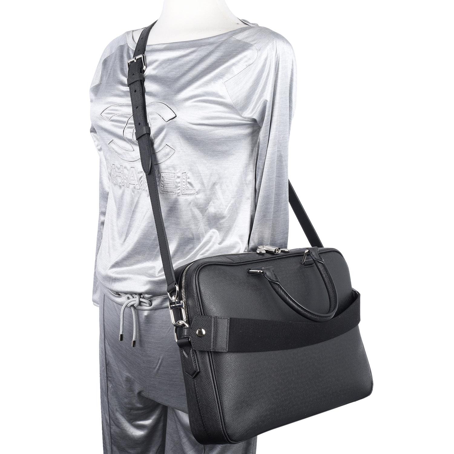 Authentique, déjà aimé Louis Vuitton Taiga Porte-Documents Business Messenger Bag en noir. Un LV se trouve sur le devant du sac, dans le coin droit.

Ce porte-documents se compose de cuir de veau noir, de poignées en cuir roulées, d'une sangle à