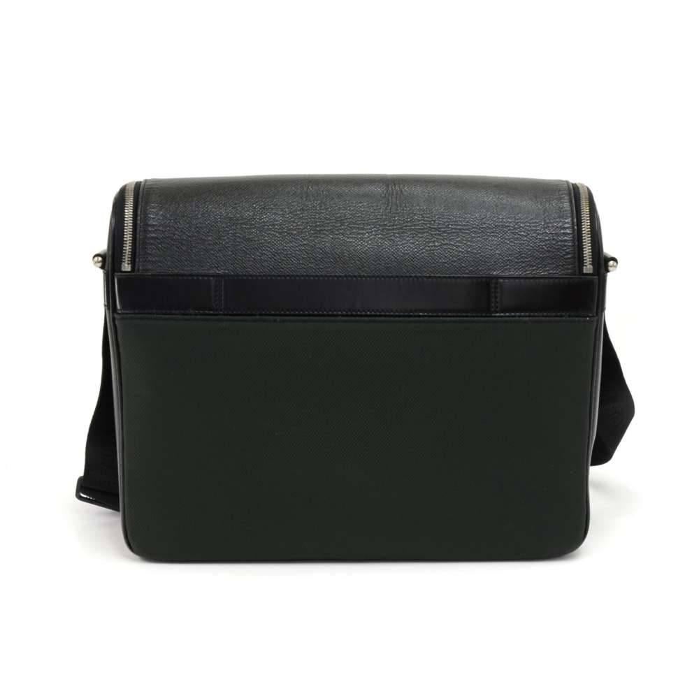 Louis Vuitton Taimyr messenger bag in black Taiga leather. It has a flap with a double zipper in the front and 1 open pocket on the back. The back has a strip of leather to allow you to slide your bag through suitcase handles to stack it on top.