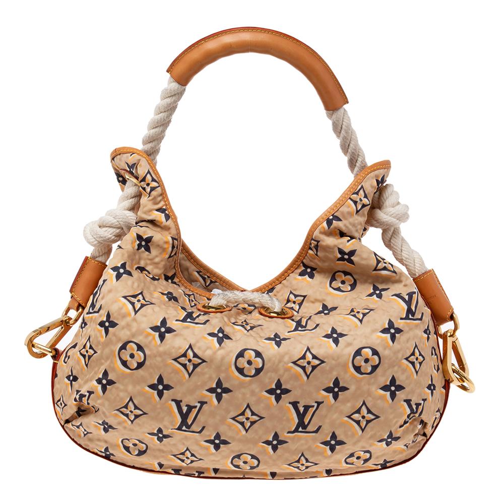 This Louis Vuitton Bulles MM bag is a rare find! It has been crafted from nylon and leather with fabric lining. Its exterior has the signature monogram, gold-tone accents, and lovely rope detailing. The top leads way to a spacious interior perfectly