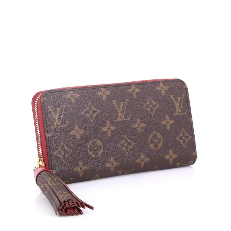 This Louis Vuitton Tassel Zippy Wallet Monogram Canvas, crafted in brown monogram coated canvas, features a wrap around tassel zipper pull and gold-tone hardware. Its zip closure opens to a magenta leather interior with multiple card slots and zip