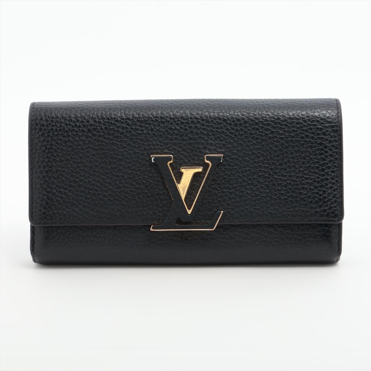 The Louis Vuitton Taurillon Capucines Long Wallet features a luxurious black exterior crafted from supple Taurillon leather, offering a refined and timeless look. Inside, the wallet reveals a striking hot pink interior that provides a bold contrast,