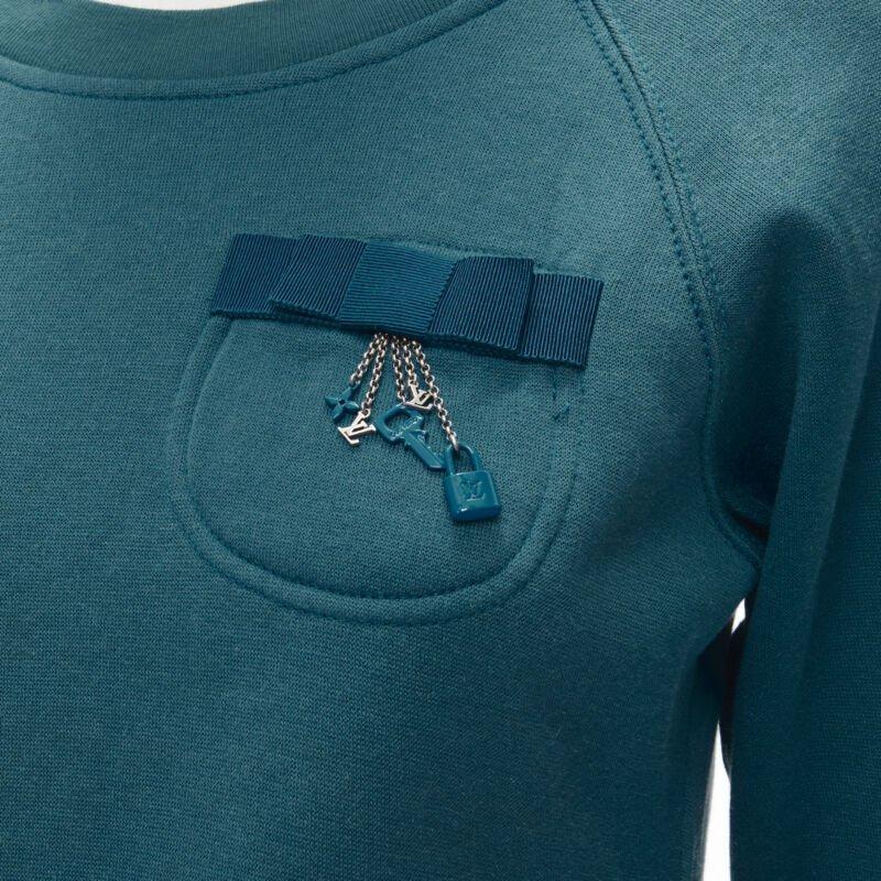 LOUIS VUITTON teal blue bow lock charm patch pocket cotton fleece sweater S
Reference: ANWU/A00651
Brand: Louis Vuitton
Material: Feels like cotton
Color: Blue
Pattern: Solid
Extra Details: Patch pocket at chest with blue grosgrain bow and