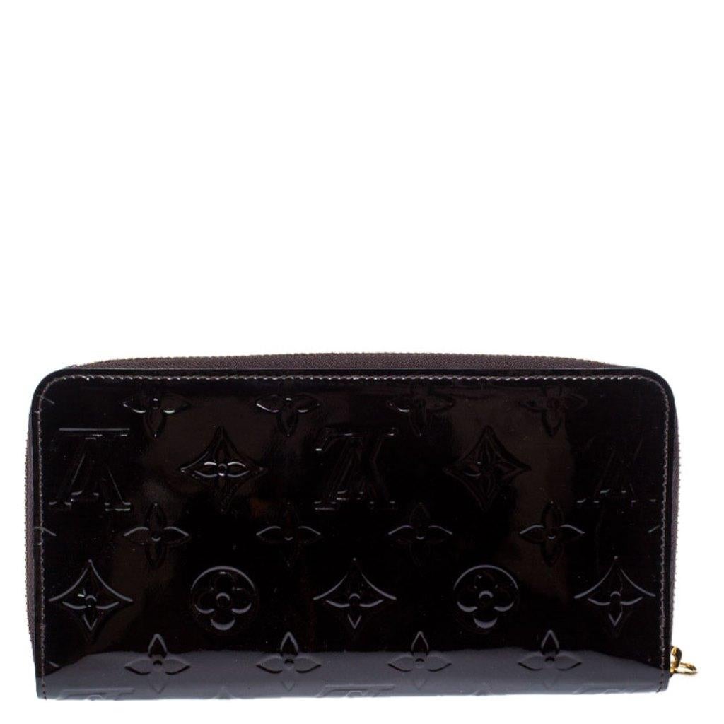 Carry your essentials in this Zippy wallet from Louis Vuitton. This glossy wallet is crafted from the brand's Monogram Vernis patent leather and comes in a lovely shade of burgundy. It has a zip closure that opens to a leather-lined interior with