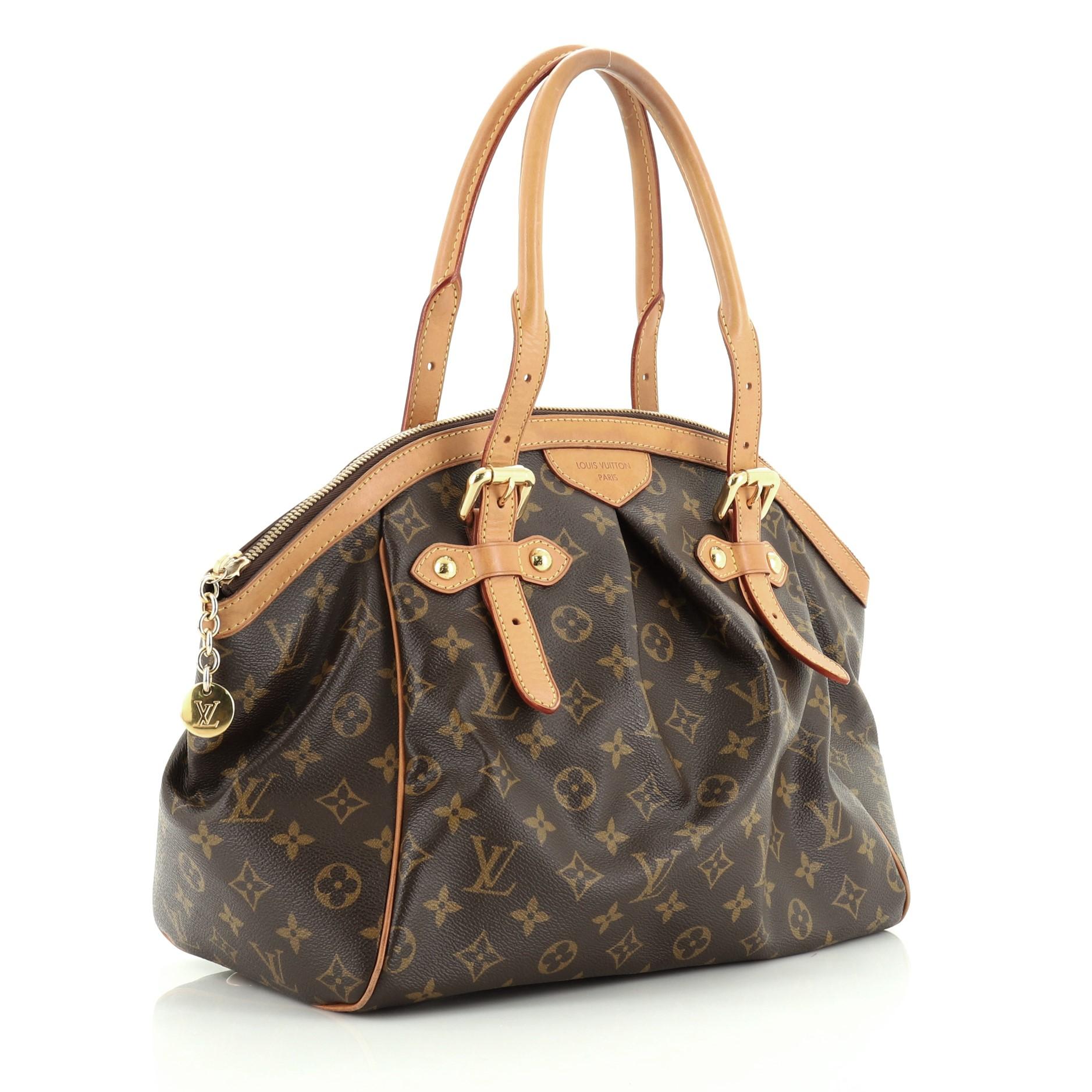 This Louis Vuitton Tivoli Handbag Monogram Canvas GM, crafted from brown monogram coated canvas, features dual rolled handles, subtle pleats in the middle, and gold-tone hardware. Its zip closure opens to a brown fabric interior with slip pockets.