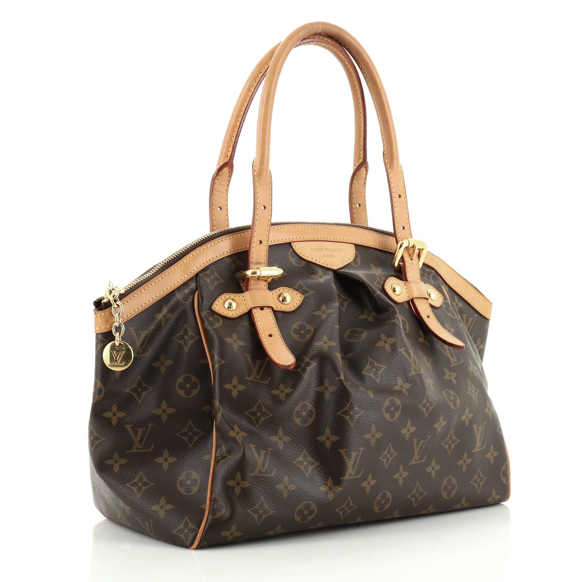 This Louis Vuitton Tivoli Handbag Monogram Canvas GM, crafted from brown monogram coated canvas, features dual rolled handles, subtle pleats in the middle, and gold-tone hardware. Its zip closure opens to a brown fabric interior with slip pockets.