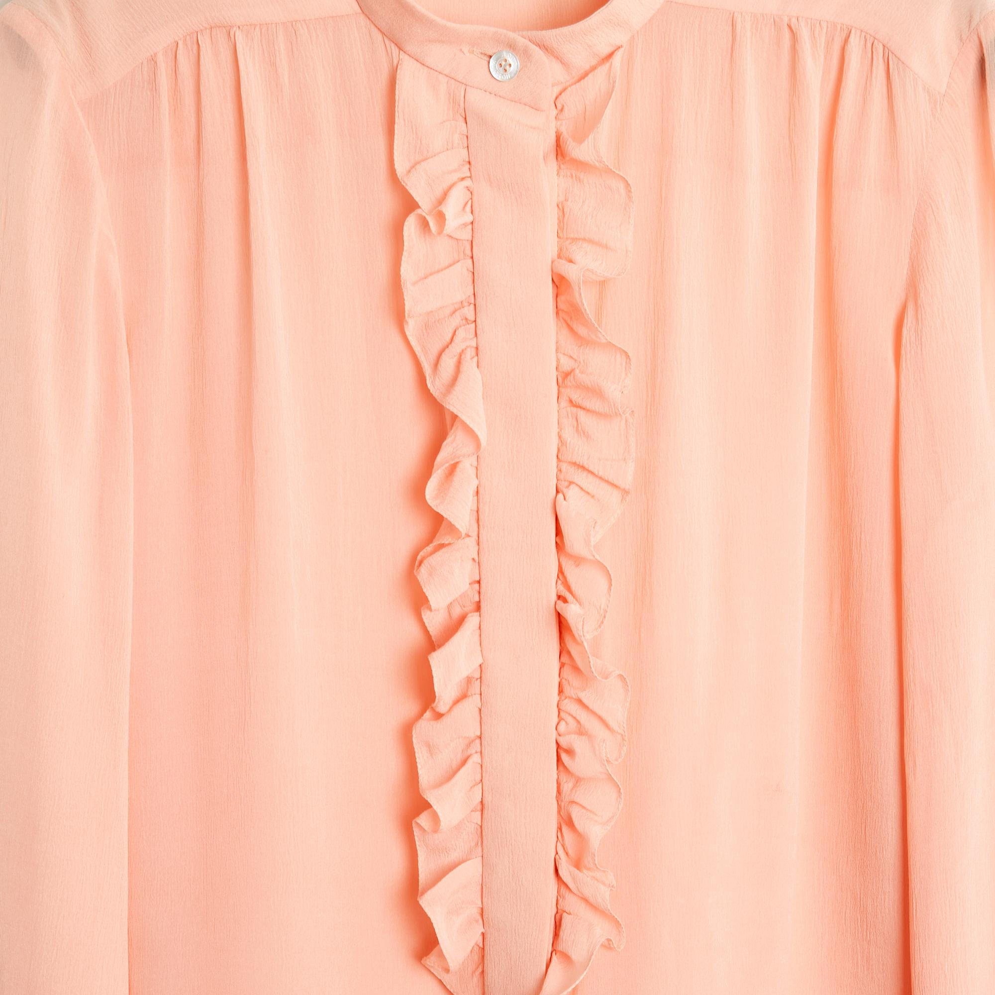 Top blouse Louis Vuitton en crêpe de soie rose légèrement pêche, petit col montant bordé de volants sur la bavette, fermé par 7 boutons de nacre (tous avec le logo Louis Vuitton) dont 6 sous des boutonnières cachées, manches longues fermées par 1