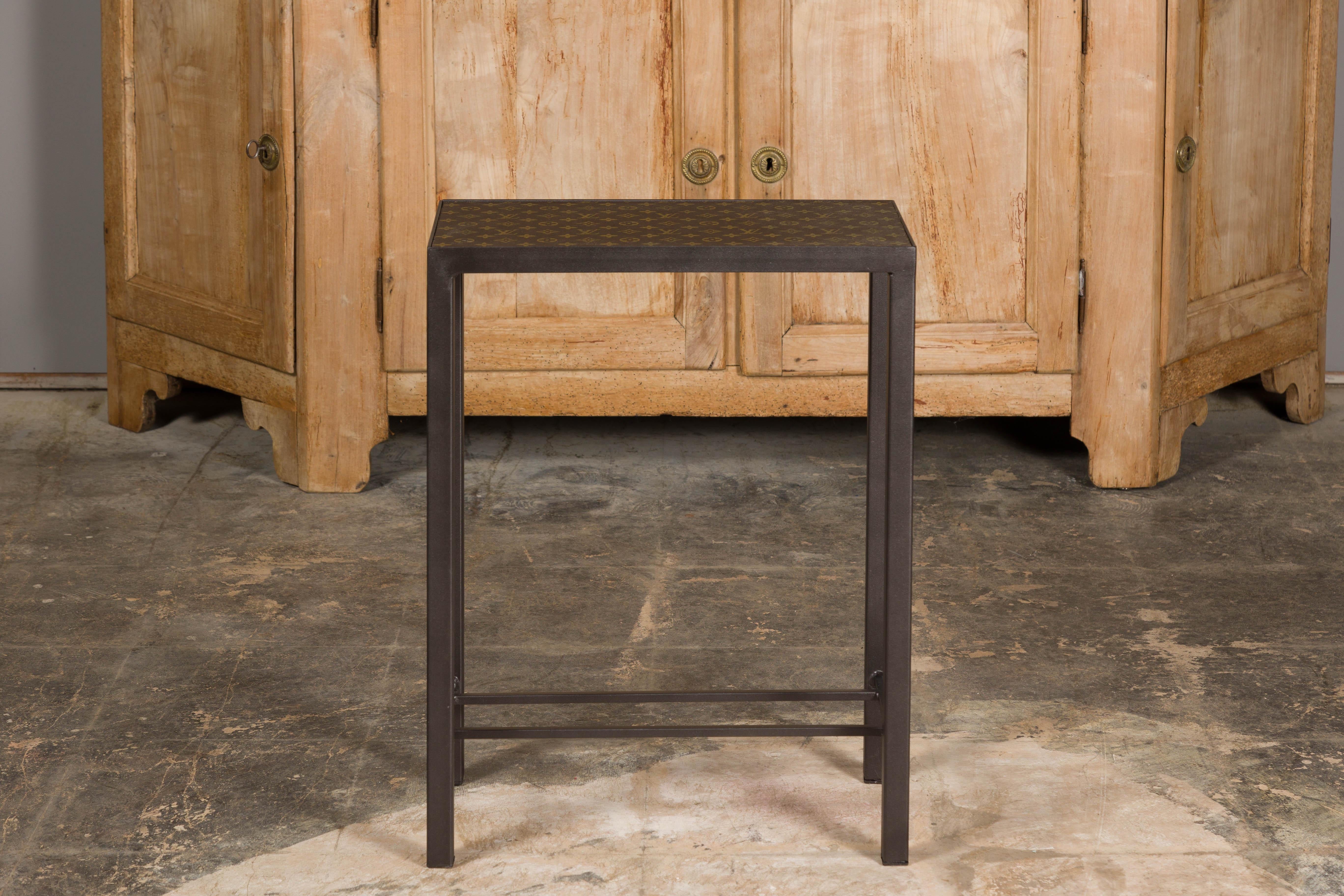 A small side table with Louis Vuitton leather top mounted on a custom metal base with cross stretchers. Immerse yourself in the epitome of luxury and craftsmanship with this stunning small side table, featuring a top adorned in iconic Louis Vuitton