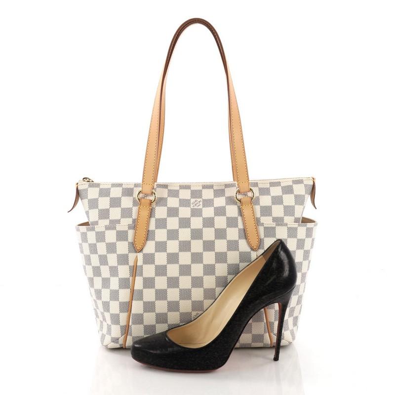 This Louis Vuitton Totally Handbag Damier PM, crafted from damier azur coated canvas, features tall cowhide leather handles and trims, two exterior lateral pockets, and gold-tone hardware. Its top zip closure opens to a beige fabric interior with