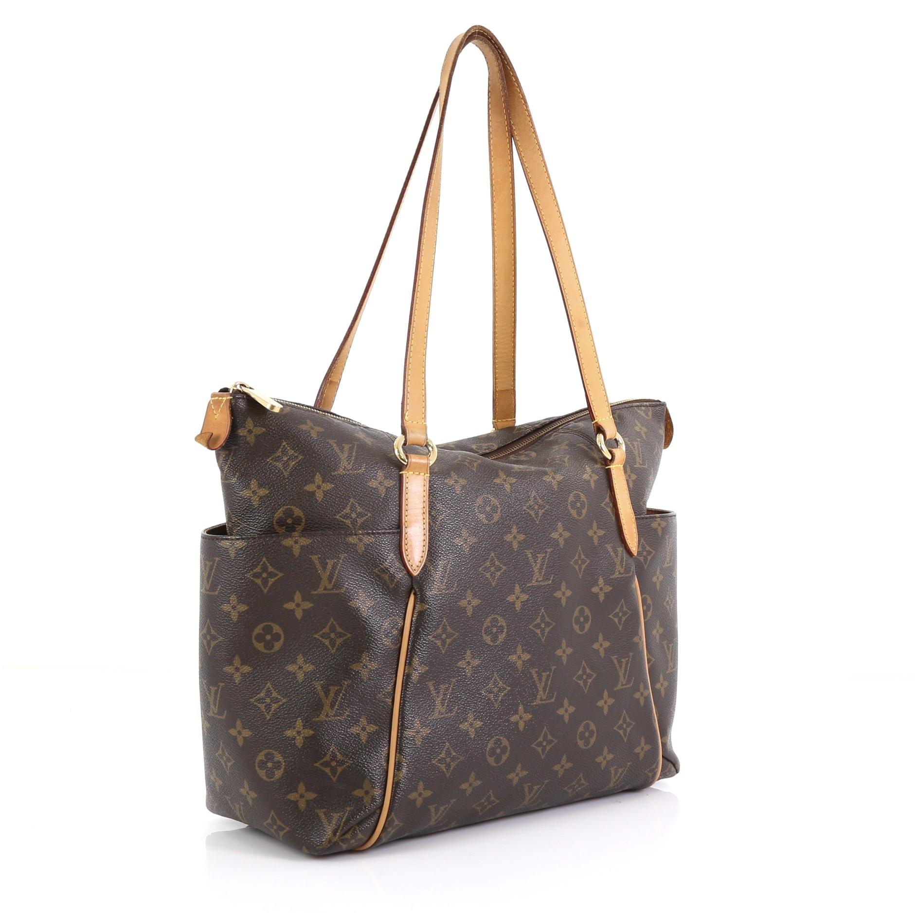 This Louis Vuitton Totally Handbag Monogram Canvas MM, crafted from brown monogram coated canvas, features tall cowhide leather handles and trim, two exterior lateral pockets, and gold-tone hardware. Its zip closure opens to a brown fabric interior