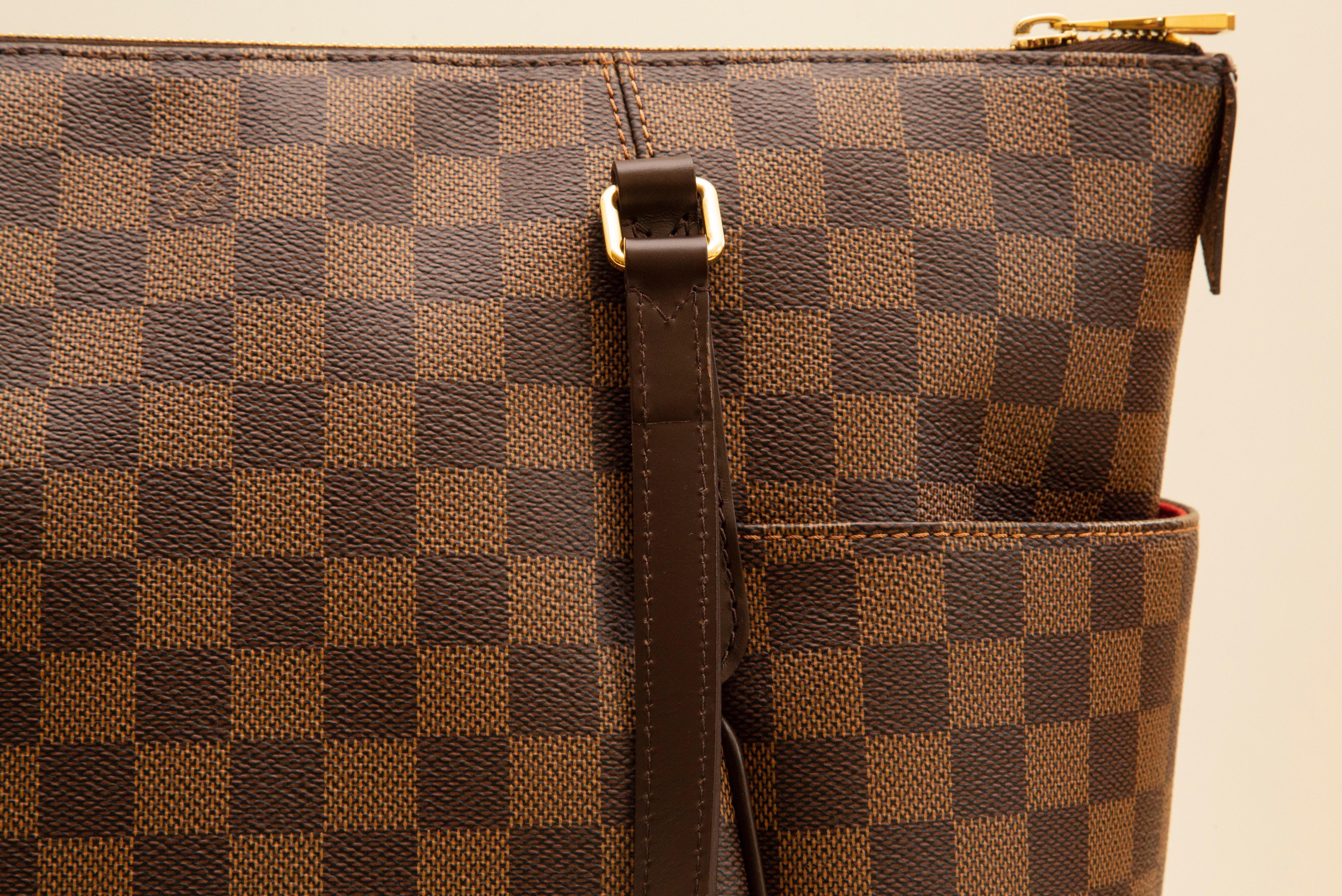 An authentic Louis Vuitton Totally MM In Damier Ebene coated canvas with brown leather trim and gold-toned hardware. Comes with a dustbag and cards. In very good condition, hardly worn, discontinued, and sold out.