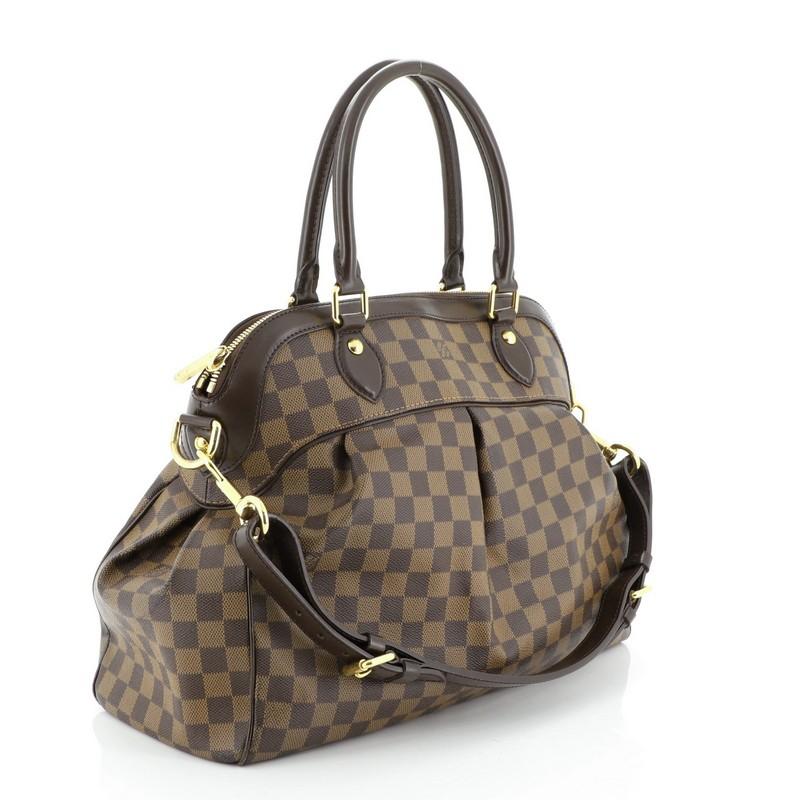This Louis Vuitton Trevi Handbag Damier GM, crafted from damier ebene coated canvas, features dual rolled handles, leather trim, and gold-tone hardware. Its zip closure opens to a red suede interior with slip pockets. Authenticity code reads: