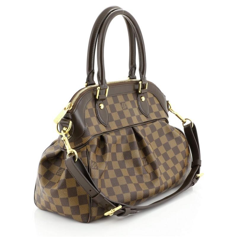 This Louis Vuitton Trevi Handbag Damier PM, crafted from damier ebene coated canvas, features dual rolled handles, leather trim, and gold-tone hardware. Its zip closure opens to a red microfiber interior with slip pockets. Authenticity code reads: