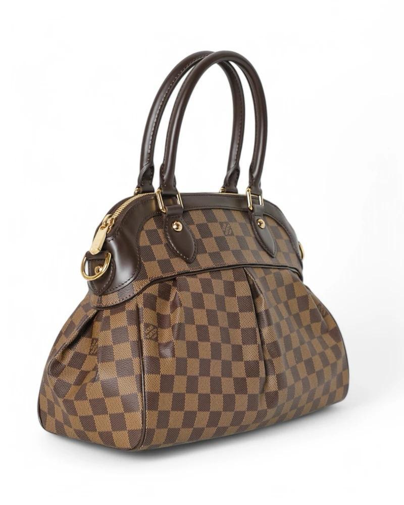 Louis Vuitton signature bag, model Trevi in size MM, made of brown canvas in the classic Damier Ebene pattern with leather inserts and gold hardware. Featuring a semi-circular zipper closure, internally lined in red suede fabric with two convenient
