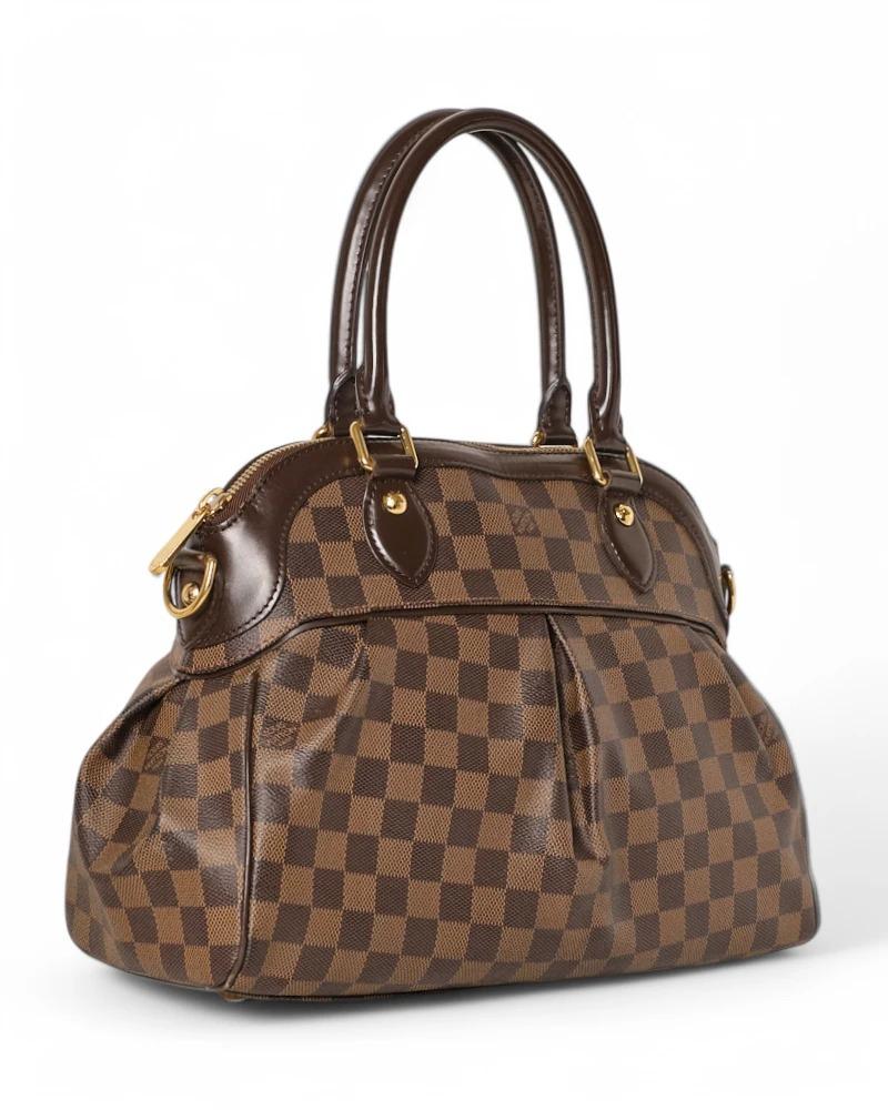 Louis Vuitton signature bag, model Trevi in size MM, made of brown canvas in the classic Damier Ebene pattern with leather inserts and gold hardware. Featuring a semi-circular zipper closure, internally lined in red suede fabric with two convenient