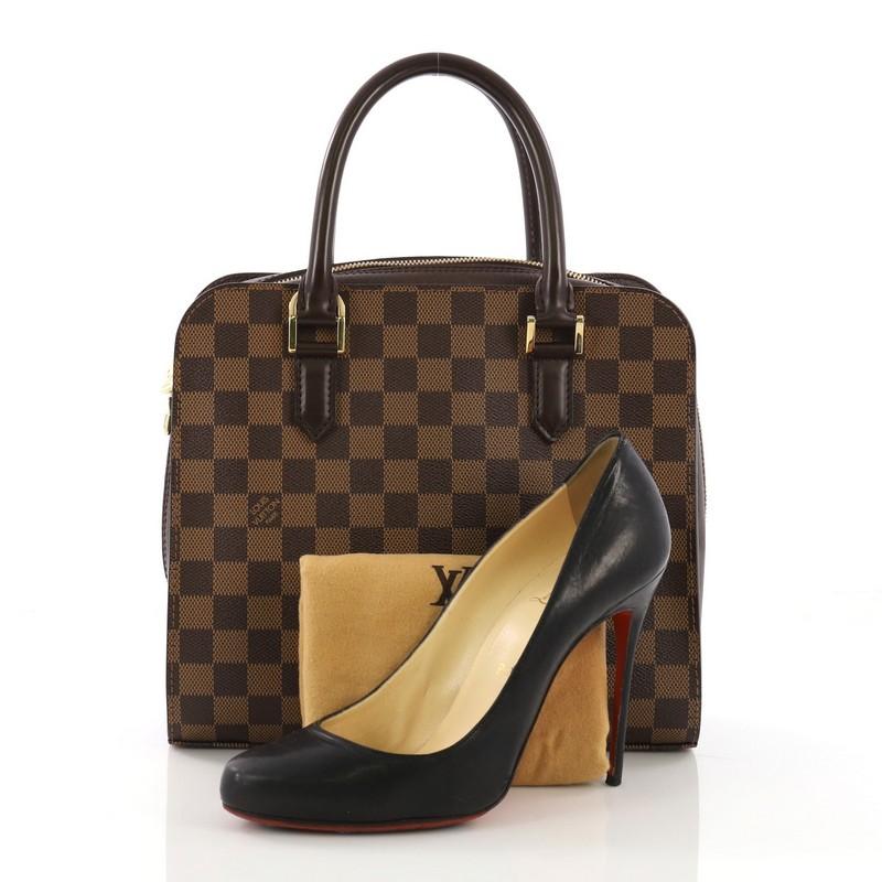 This Louis Vuitton Triana Bag Damier, crafted in damier ebene coated canvas, features dual rolled leather handles and gold-tone hardware. Its zip around closure opens to an orange fabric interior with zip pocket. Authenticity code reads: VI0024.