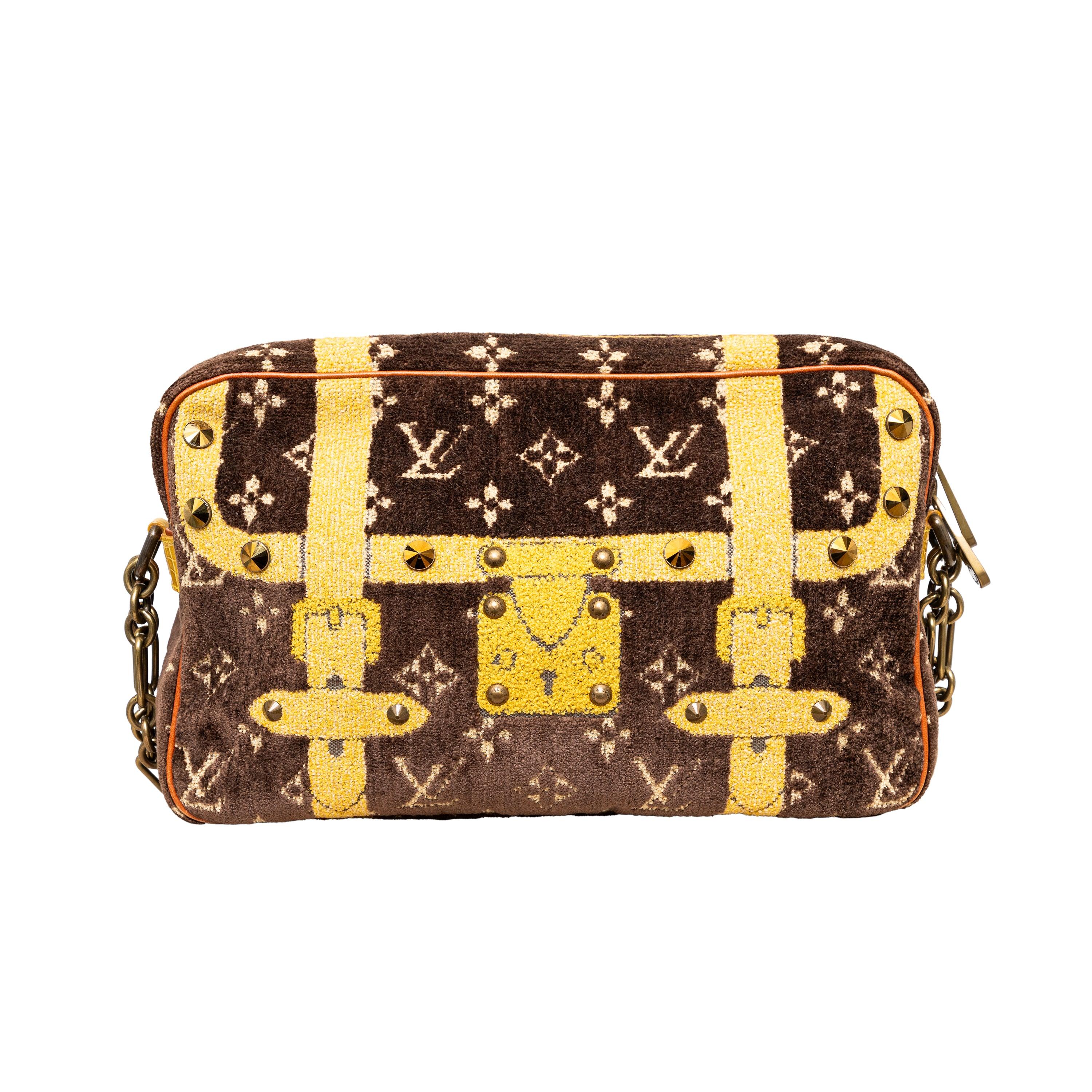 The Louis Vuitton Trompe L'Oeil Trocadero Shoulder Bag boasts a stunning monogram with the iconic travel trunk pattern, accented with studded details and golden hardware. With a top zip closure and a leather shoulder strap adorned with a chain, this