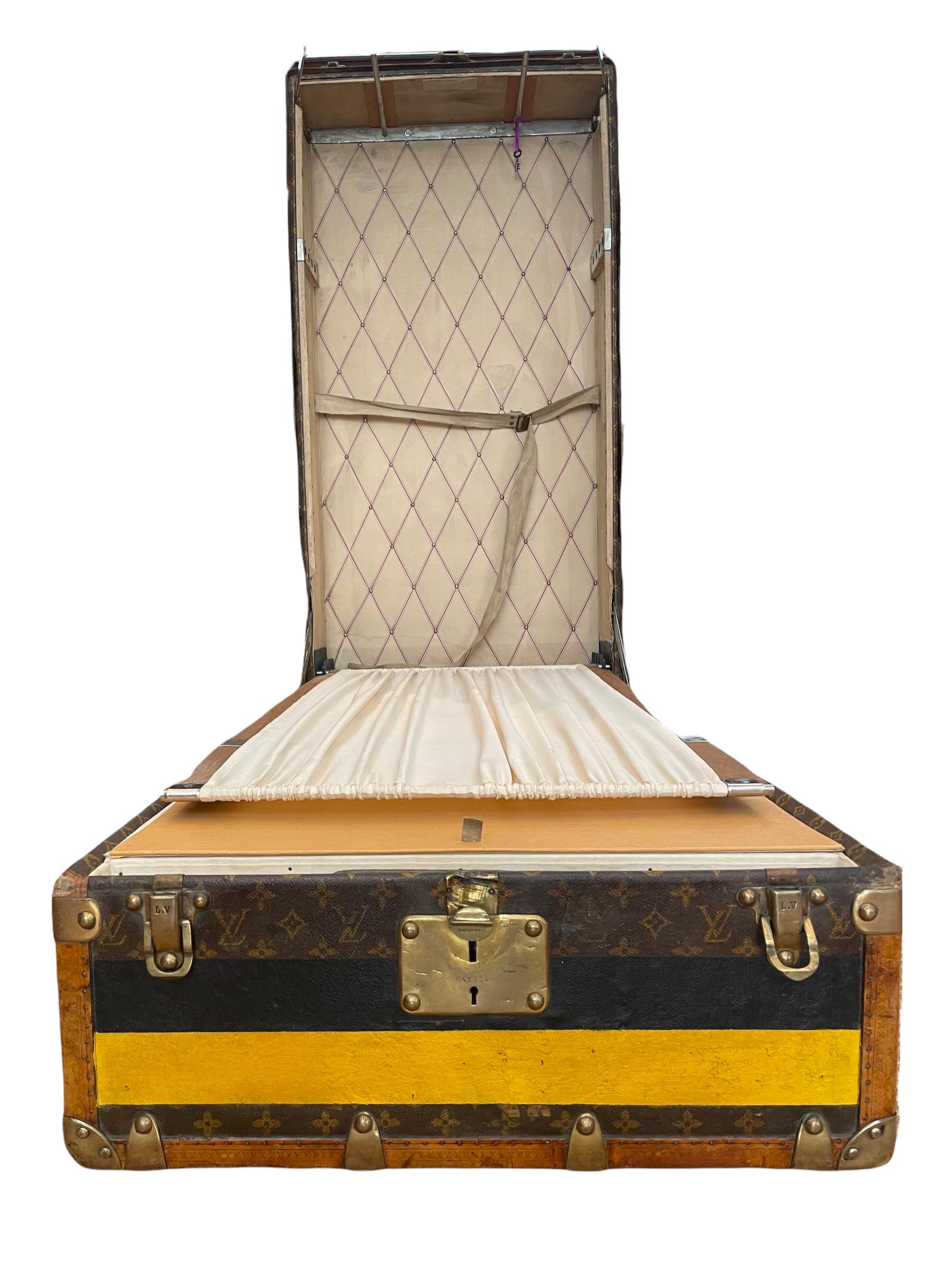 Exceptional Louis Vuitton wardrobe trunk features stenciled monogram canvas; brown loziné LV stamped solid brass locks and studs. Customized yellow and black stripes give a lot of character to this elegant piece.

The interior is original and