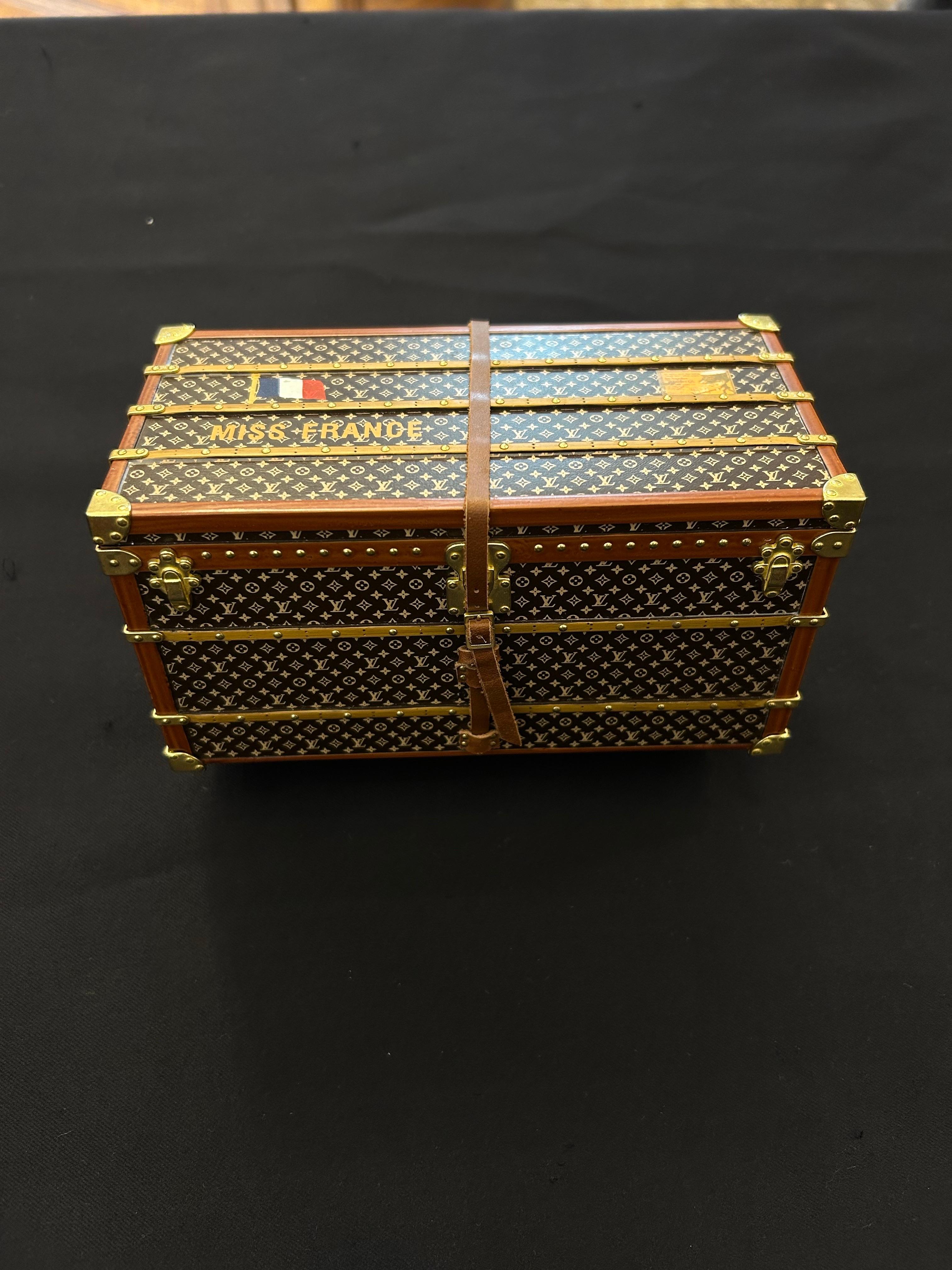 This exquisite miniature Louis Vuitton trunk is a rare and exceptional paperweight, once gifted exclusively to VIP clients and never available for public sale. It is a precise 1:7 scale replica of the monogram trunk presented to Miss France in 1927,