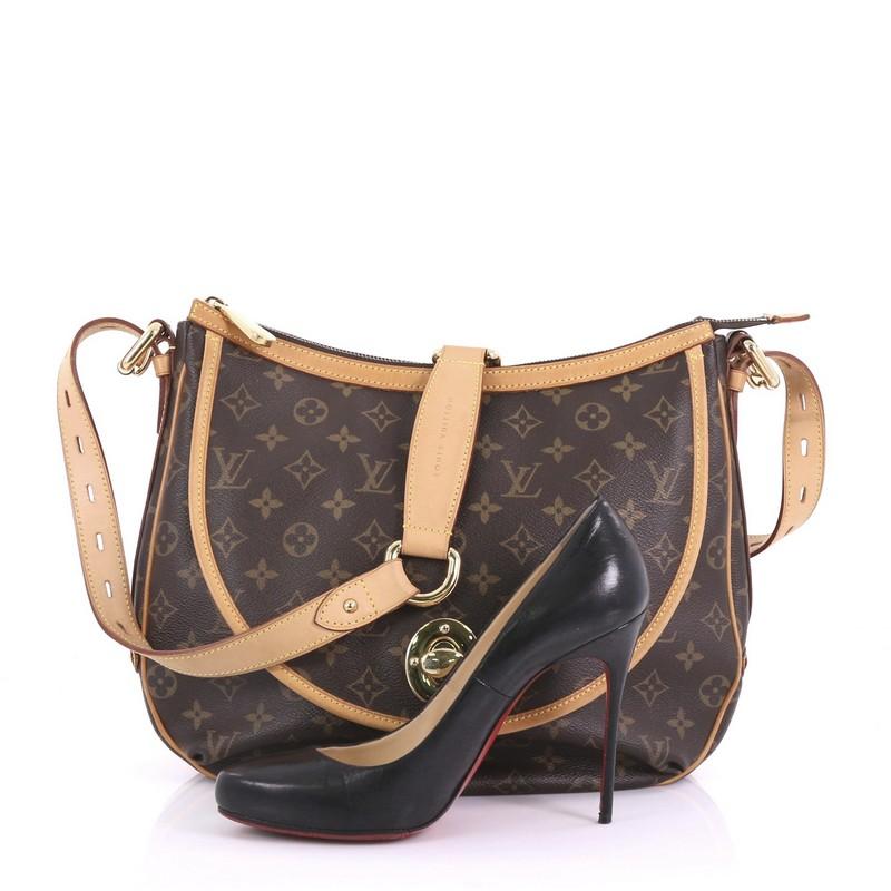 This Louis Vuitton Tulum Handbag Monogram Canvas GM, crafted from brown monogram coated canvas, features vachetta leather strap and trim, front flap pocket with turn-lock closure, and gold-tone hardware. Its zip closure opens to a brown fabric