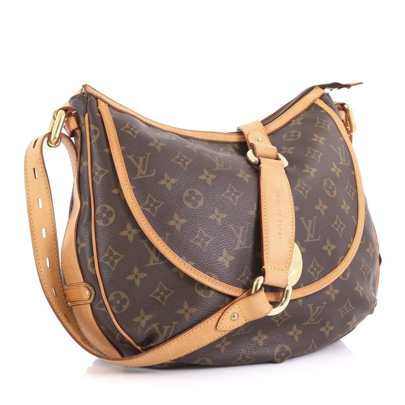 This Louis Vuitton Tulum Handbag Monogram Canvas GM, crafted from brown monogram coated canvas, features vachetta leather strap and trim, front flap pocket with turn-lock closure, and gold-tone hardware. Its zip closure opens to a brown fabric